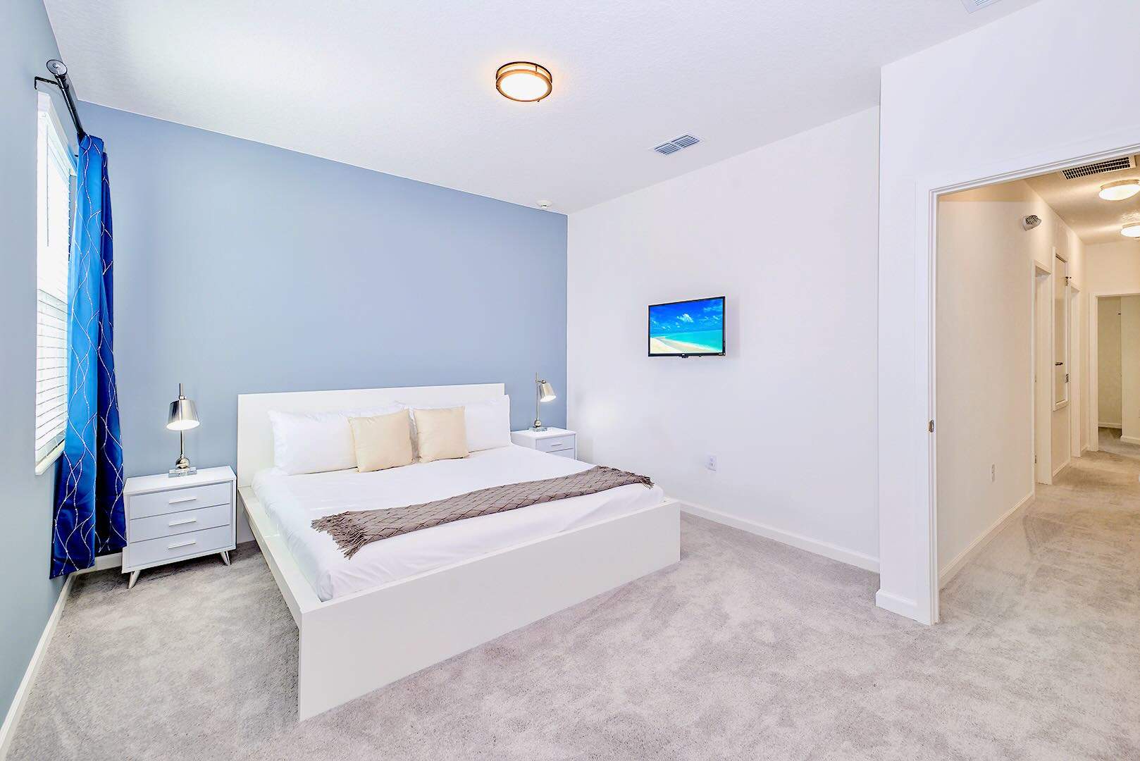 Spacious Bedroom With Soft Blue Accents And Smart TV For Relaxation