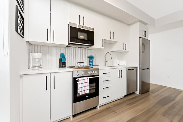 Fully Equipped Kitchen With Sleek White Cabinets And Stainless Steel Appliances