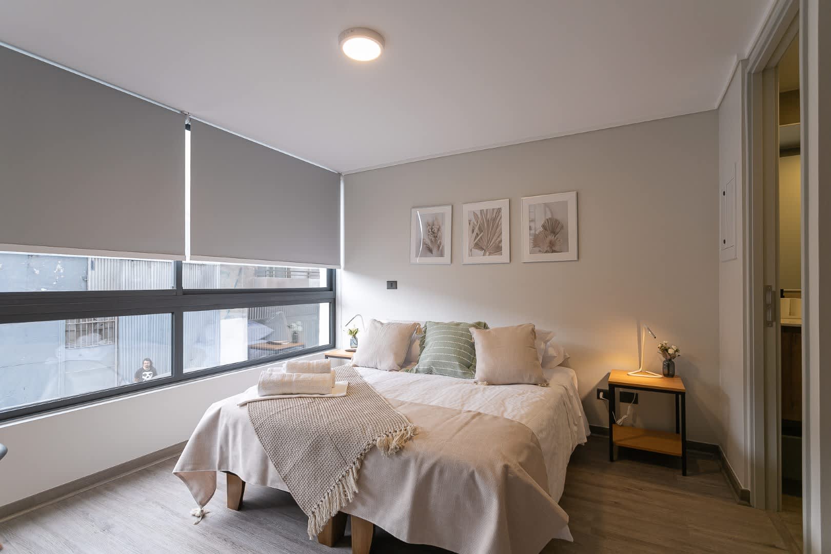 Relax in this cozy, well-lit bedroom with modern decor and large windows, perfect for unwinding after a day exploring the city.
