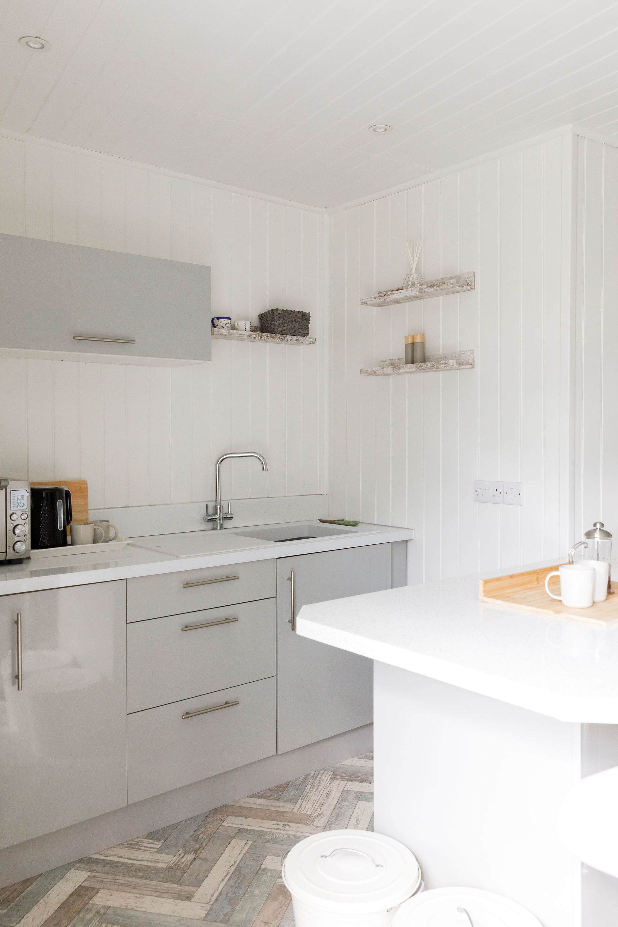The grey cabinetry and white wood gives this kitchenette a clean and spacious feel.
