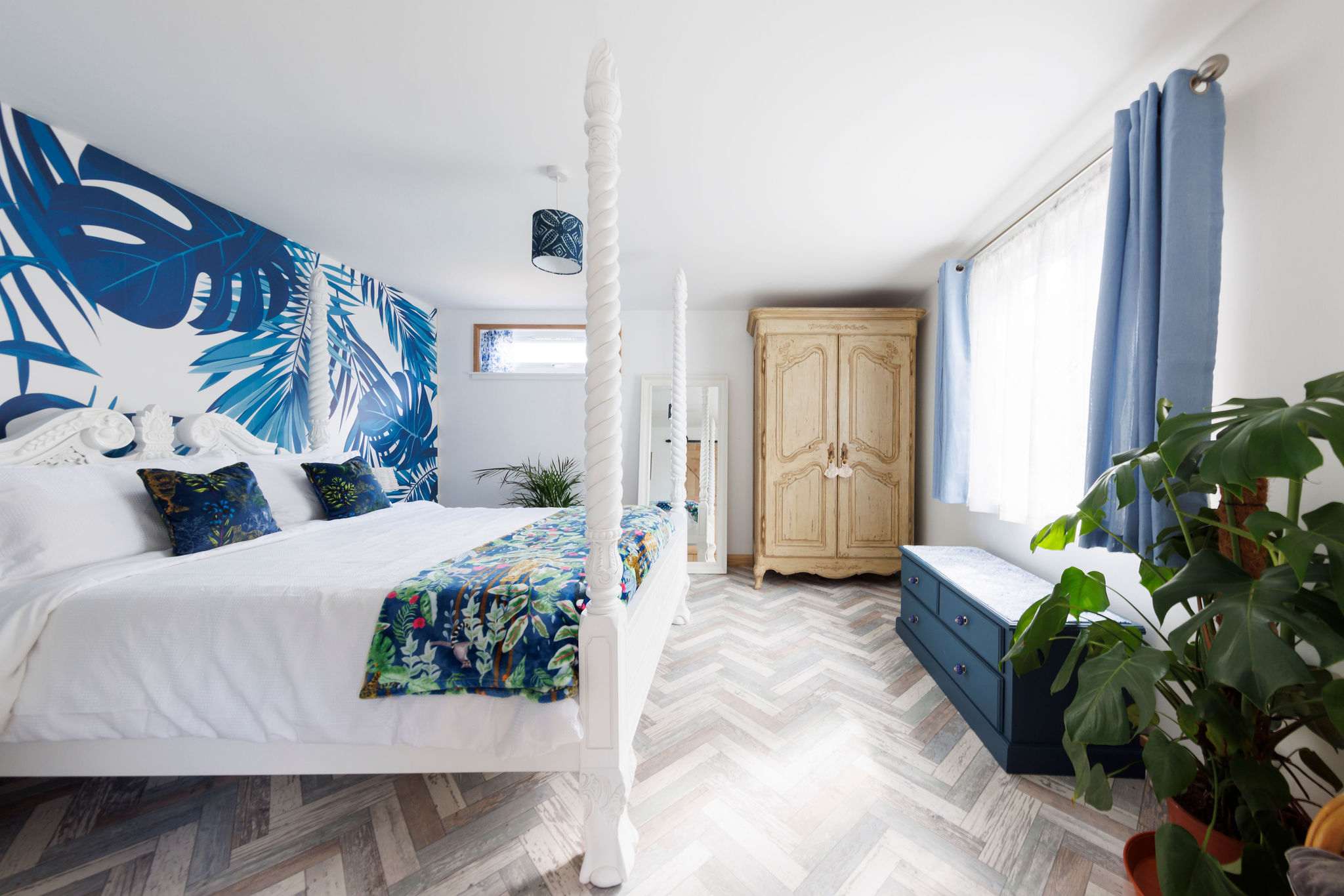 When night falls, retreat to the stylish king bedroom, beautifully decorated with vibrant wallpaper, cushions, throws and house plants.