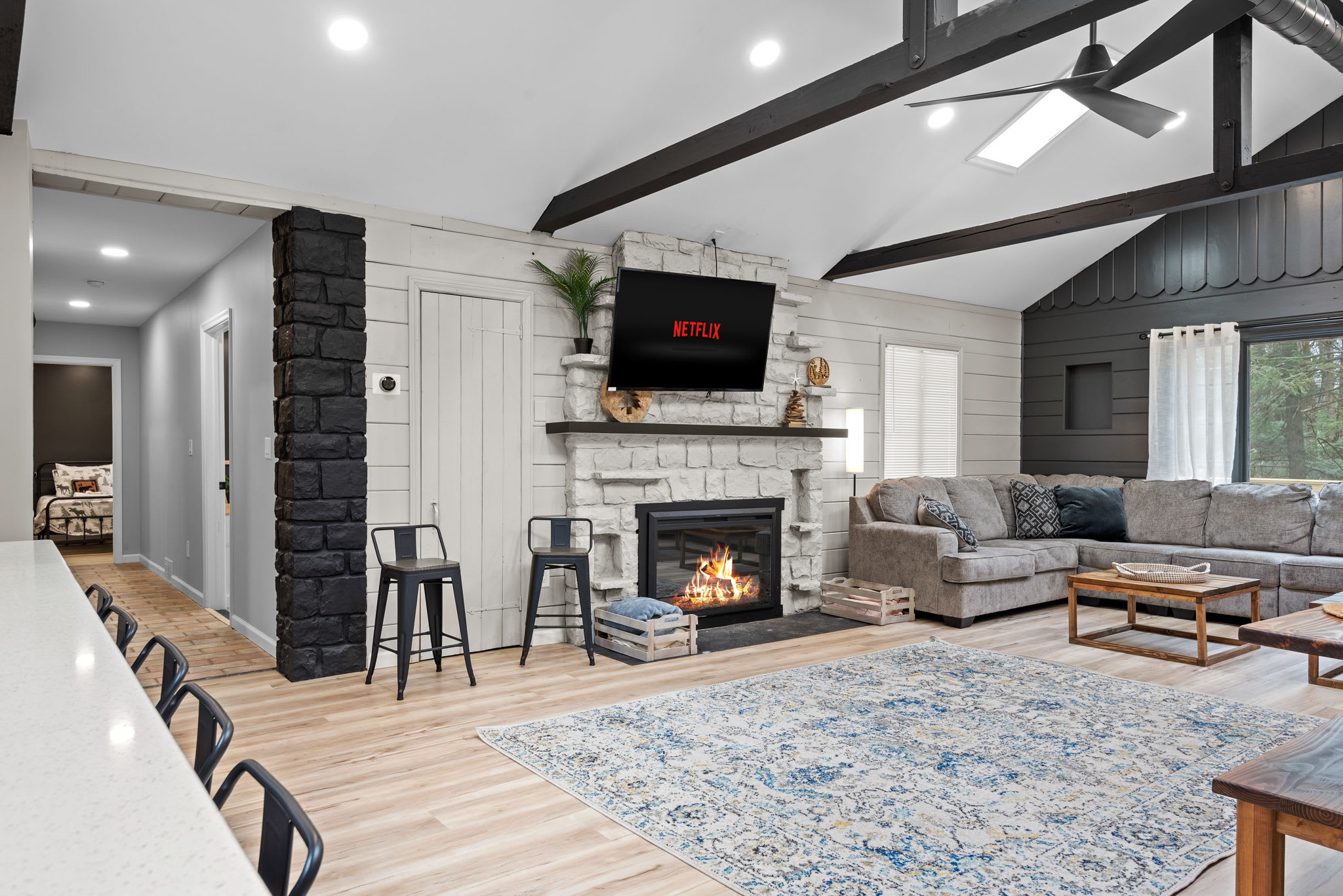 Grand & Cozy Living Space
Vaulted ceilings, exposed beams, and a stunning stone fireplace make this living area both elegant and inviting. Curl up on the plush seating and enjoy a movie night by the fire.