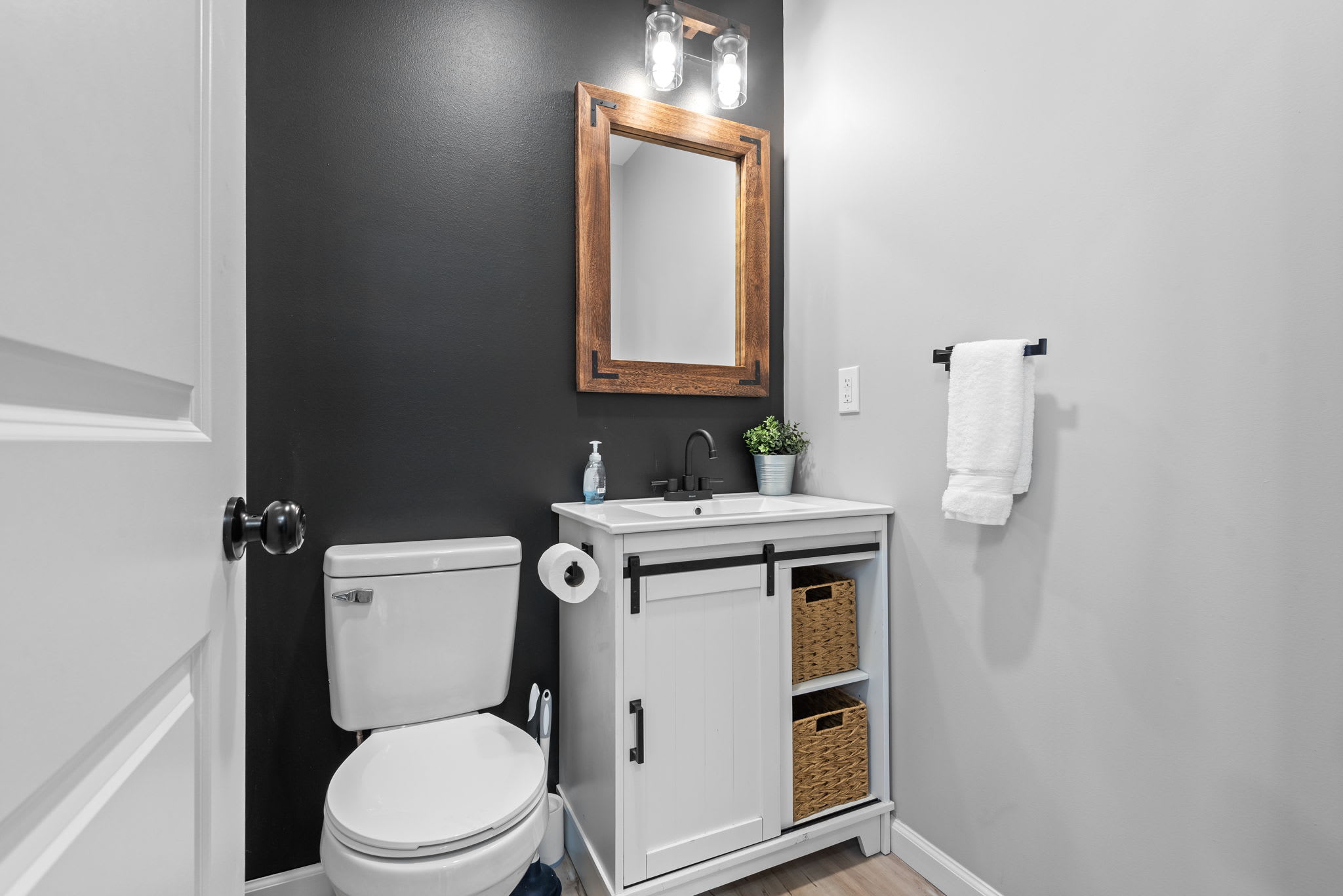 Designed with convenience in mind, this bathroom offers a clean and modern aesthetic with bold contrast walls and charming farmhouse-style accents.