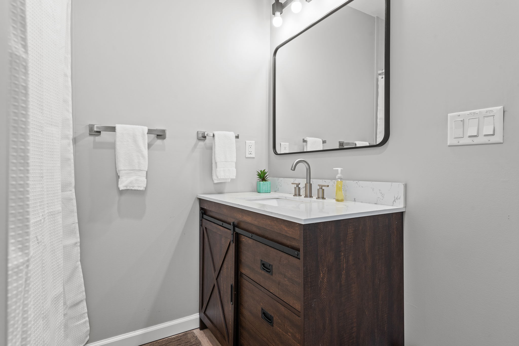 Thoughtfully designed with dark wood accents, a large mirror, and soft lighting this bathroom blends functionality with modern style.
