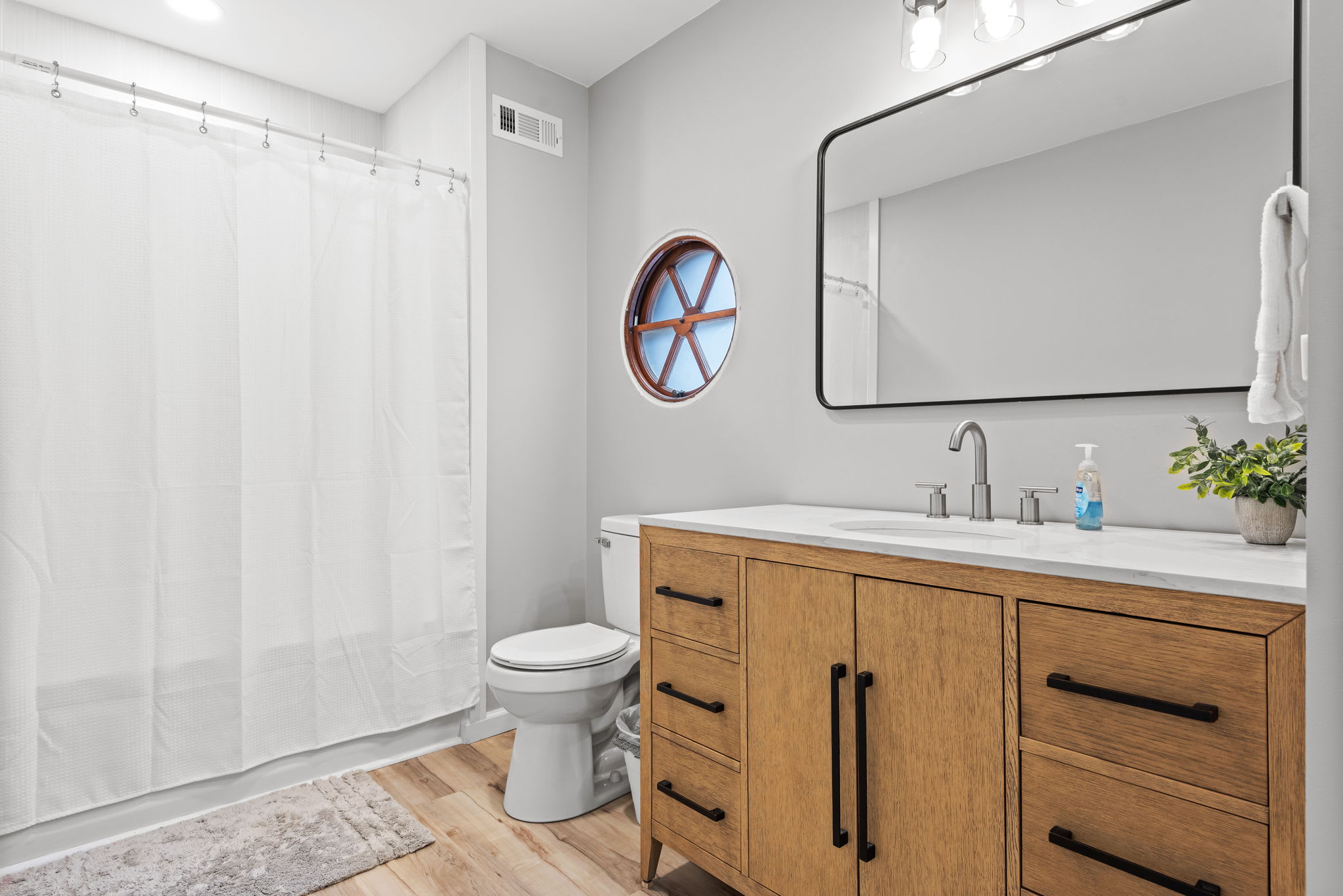 Rustic Meets Modern in the Bathroom
This bright and spacious bathroom features a sleek vanity with warm wood tones, a large mirror, and nautical-inspired details for a fresh and relaxing atmosphere.