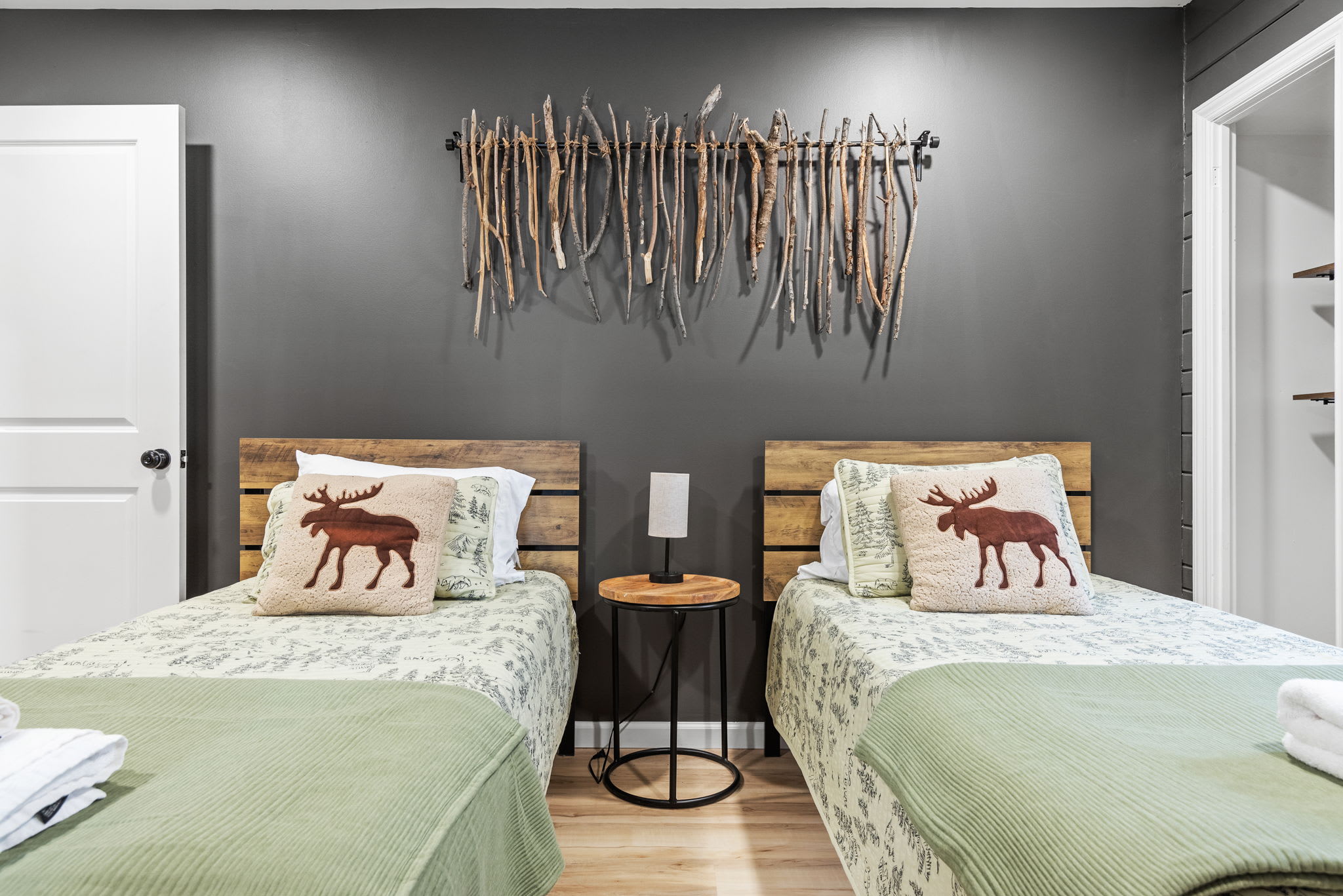 Perfect for friends or family, this bed arrangement offers a mix of comfort and style with playful wildlife-themed pillows and a unique driftwood wall accent.