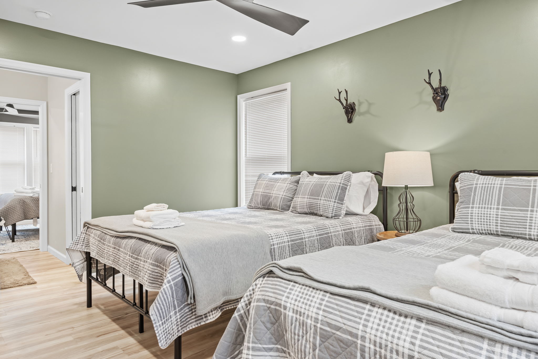 Thoughtful details like antler-inspired wall sconces, cozy plaid bedding, and a soft neutral color palette bring a balance of rustic charm and modern elegance.