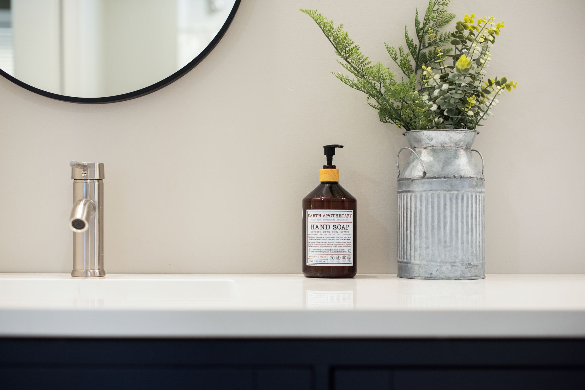 A beautifully designed bathroom with a navy blue double vanity, elegant round mirrors, and minimalist decor combining functionality with a touch of sophistication.
