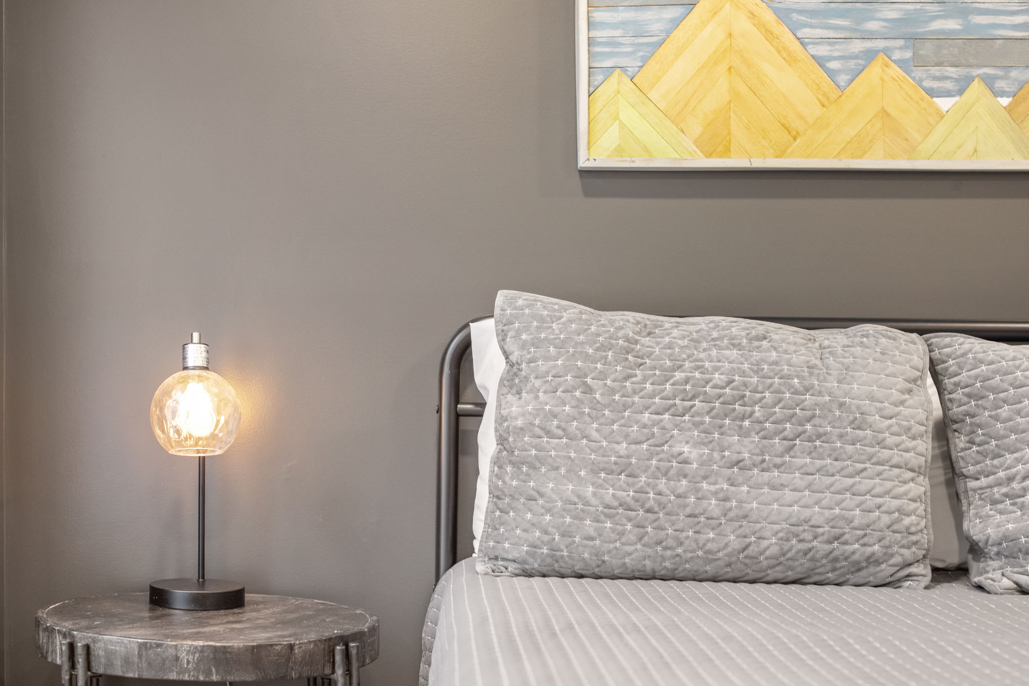Thoughtful Details for a Relaxing Stay
A beautifully arranged nightstand with a warm glowing lamp, soft textures, and contemporary artwork adds a touch of personality to this peaceful retreat.
