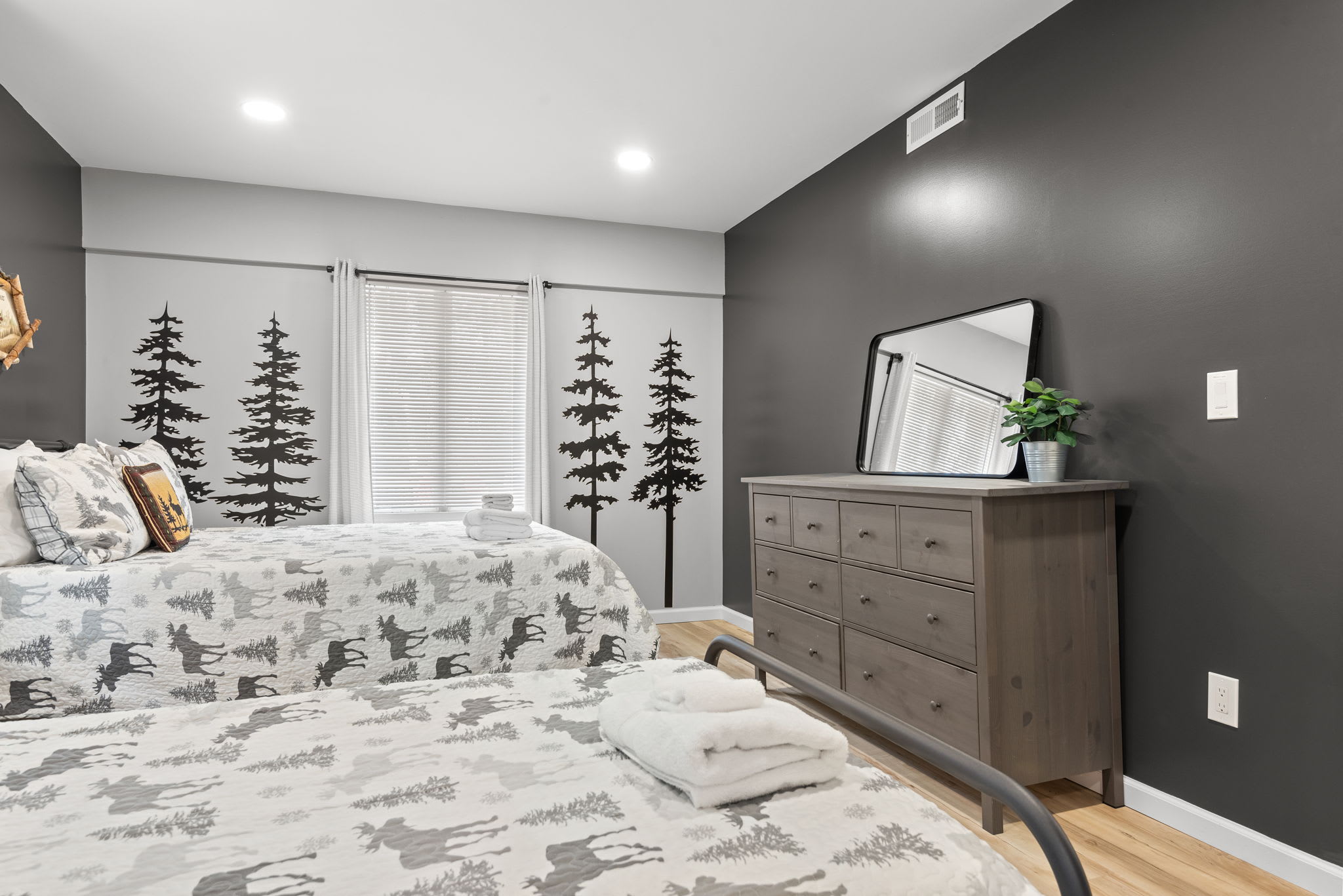 Spacious & Stylish Lodge-Inspired Room
Featuring beds, nature-inspired decor, and a dark accent wall, this space is both cozy and functional perfect for a peaceful night’s sleep.