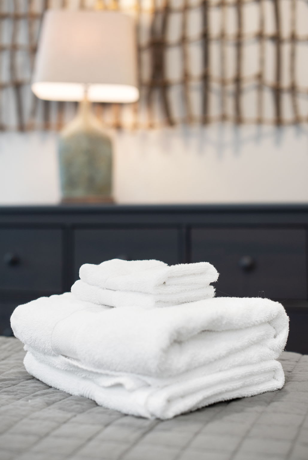 Fresh linens, soft lighting, and warm textures create a cozy atmosphere for guests to unwind in this stylish bedroom.