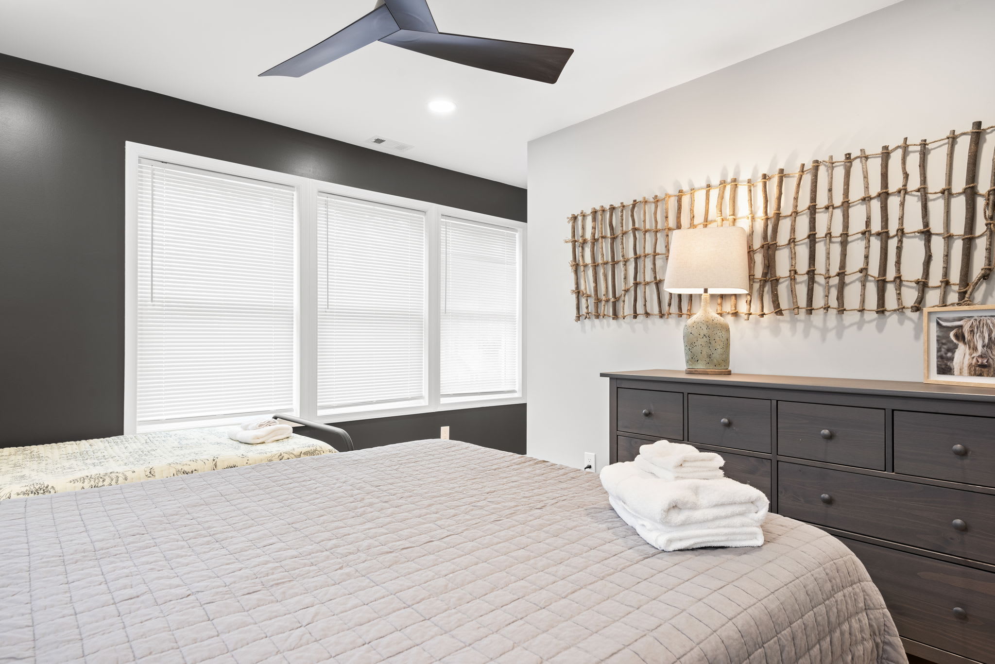 A perfect blend of modern and cozy, this bedroom features a soft color palette, warm wooden accents, and a statement ceiling fan for added comfort.