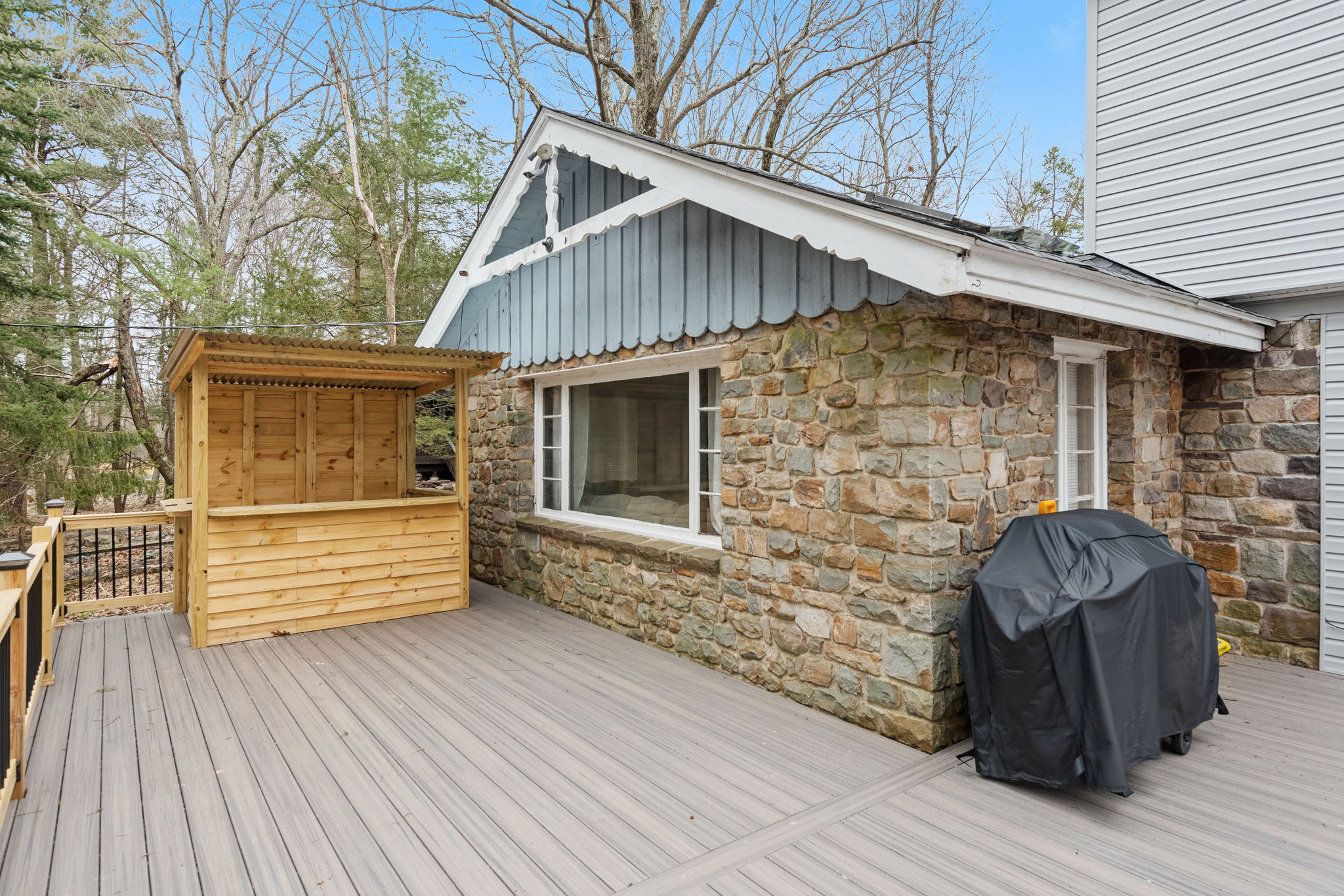 A charming blend of rustic stonework and modern touches, this home’s exterior features a unique wooden bar, perfect for outdoor entertaining and enjoying the fresh mountain air.