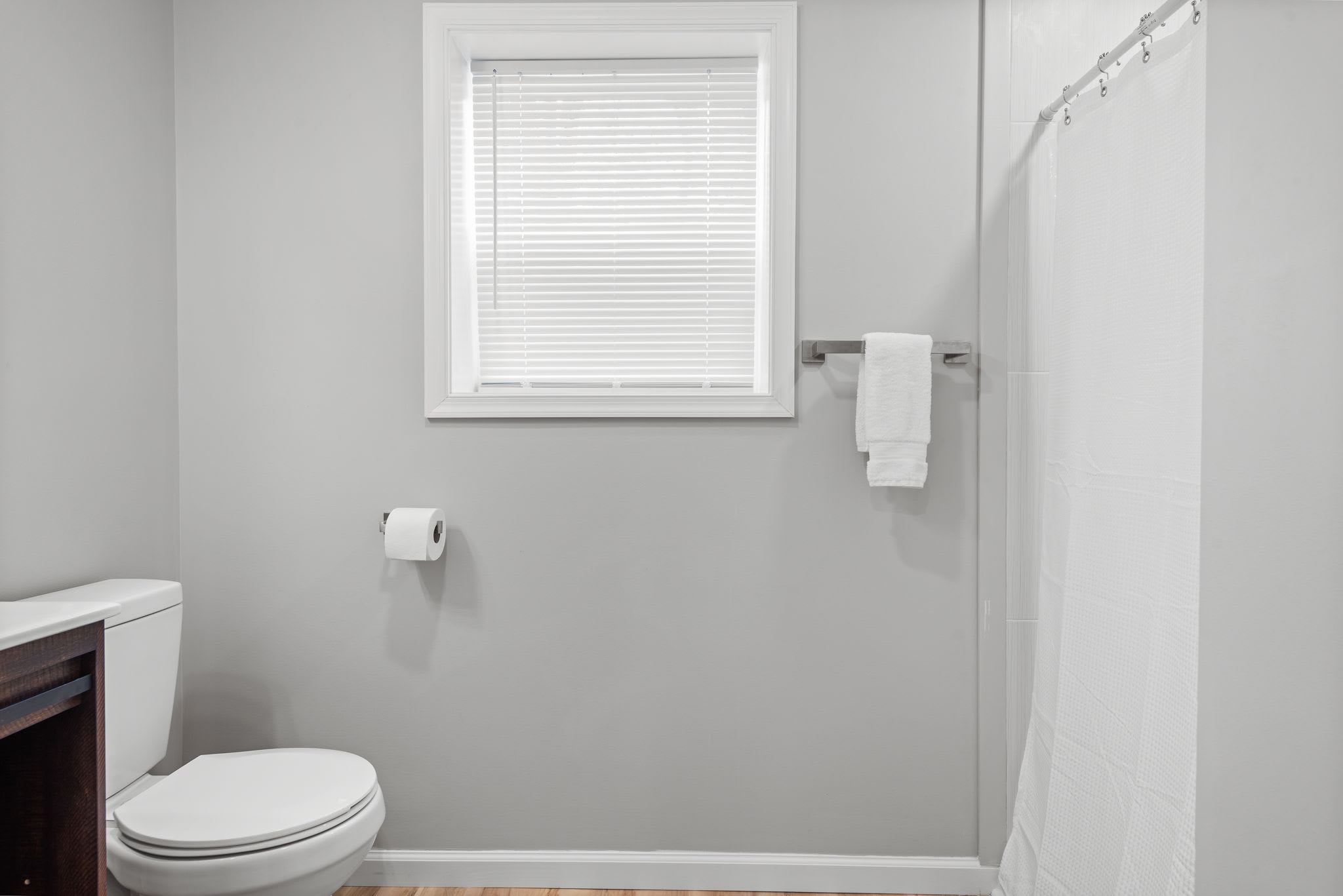 A clean and modern bathroom featuring a walk-in shower, soft neutral tones, and a bright window, making it a relaxing and functional space.
