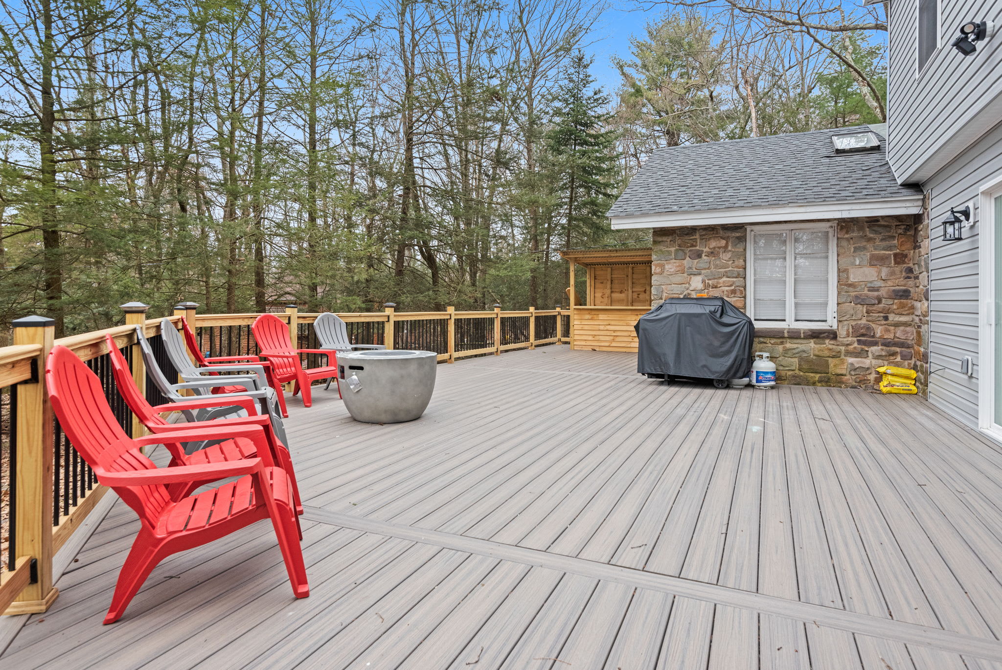 Expansive Outdoor Deck
Step outside and breathe in the fresh air on this spacious deck, complete with colorful Adirondack chairs, a grill, and serene wooded views, perfect for morning coffee or evening gatherings.