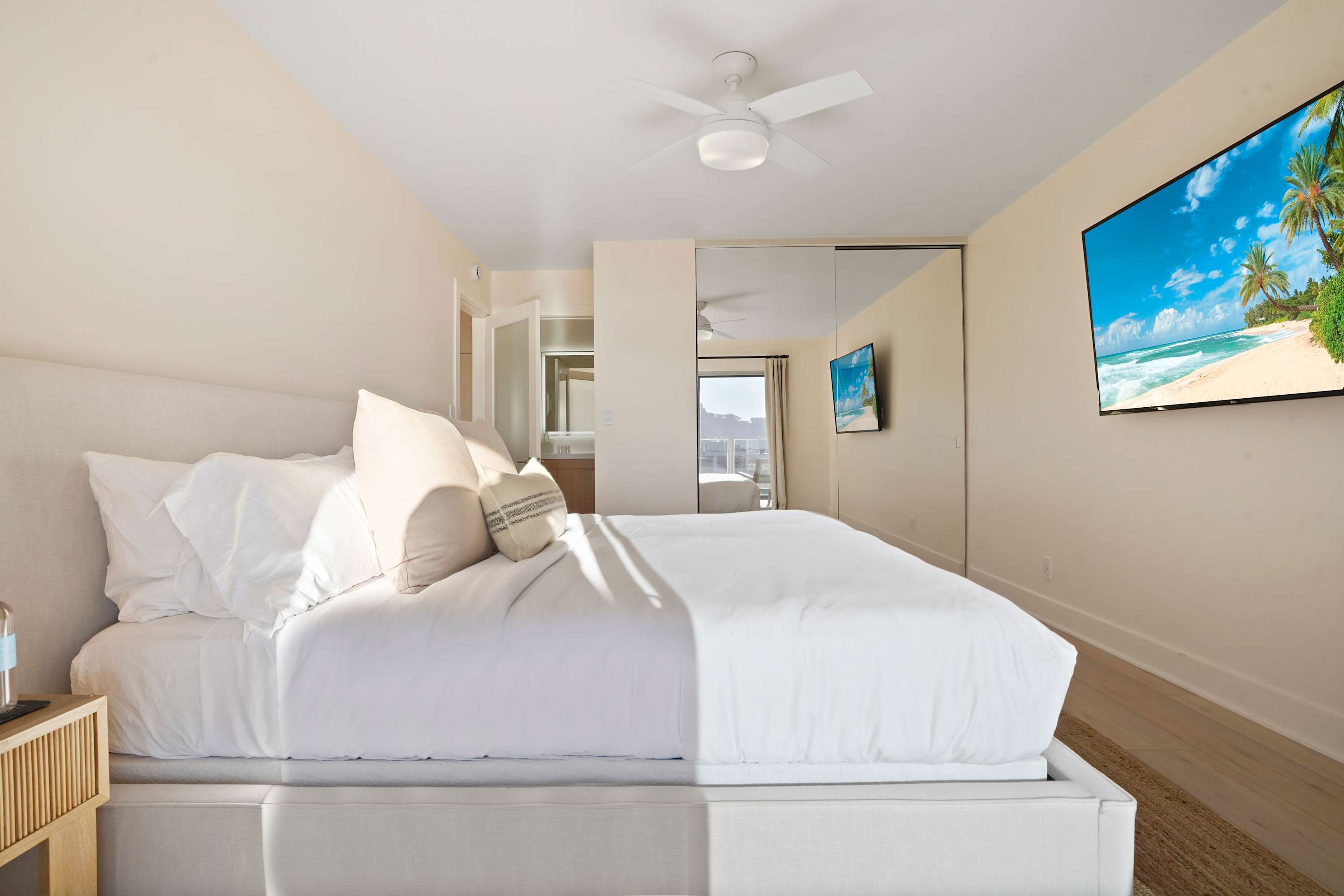 Spacious bedroom with a king-size bed, mirrored closet, and calming beach-inspired decor.