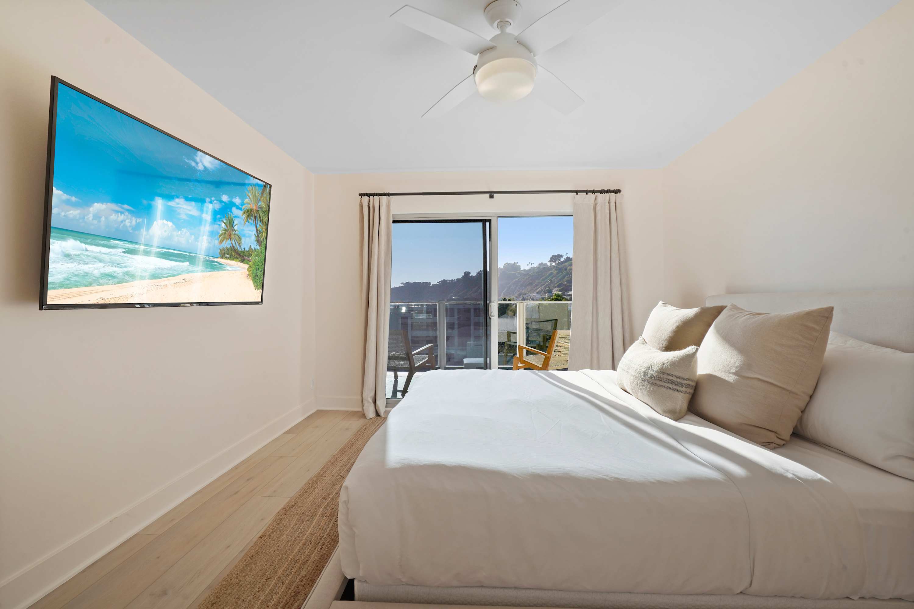 Relax in a well-appointed bedroom featuring plush bedding and a large wall-mounted TV.