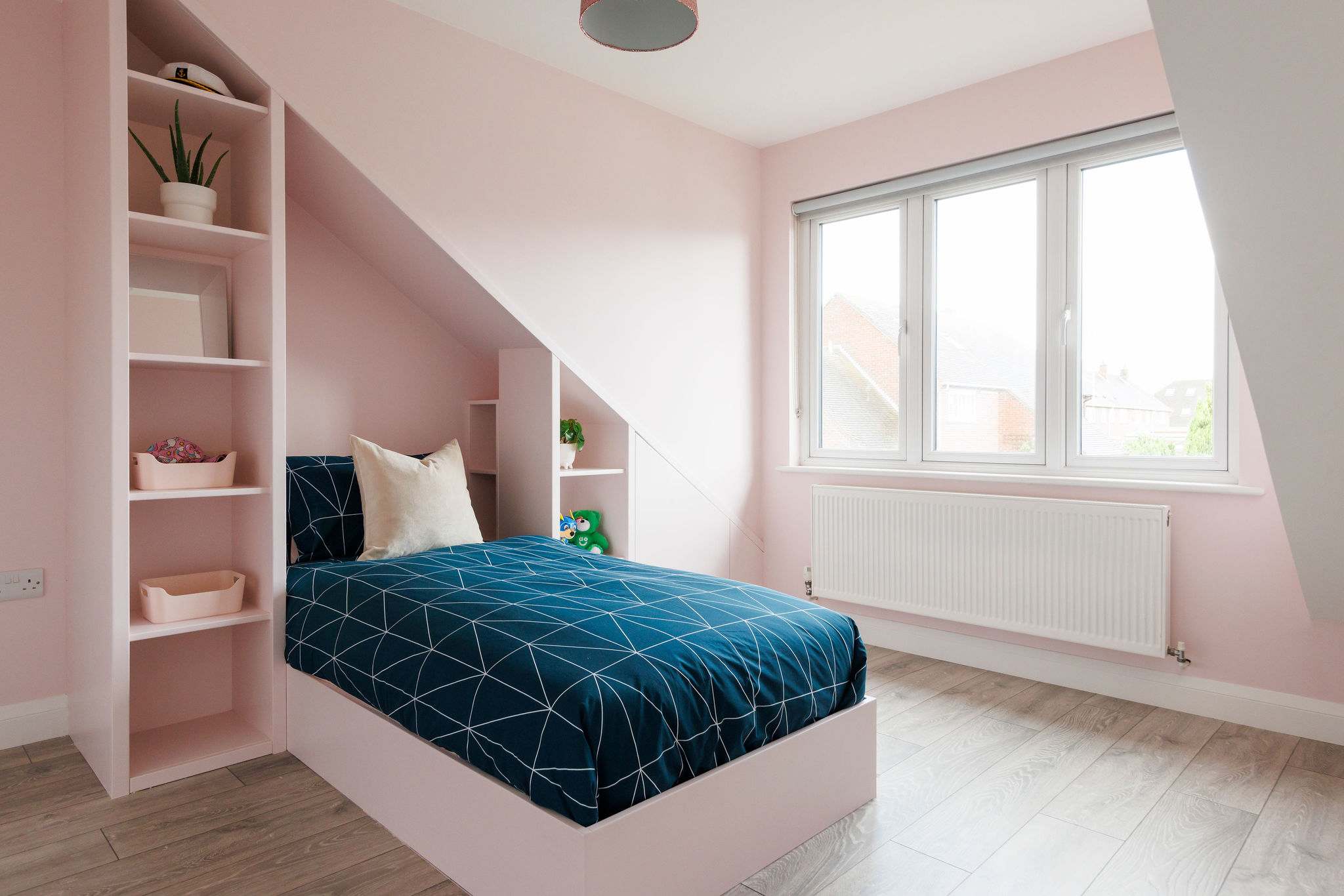 A single bedroom decorated in pale pink, with shelving for your belongings.