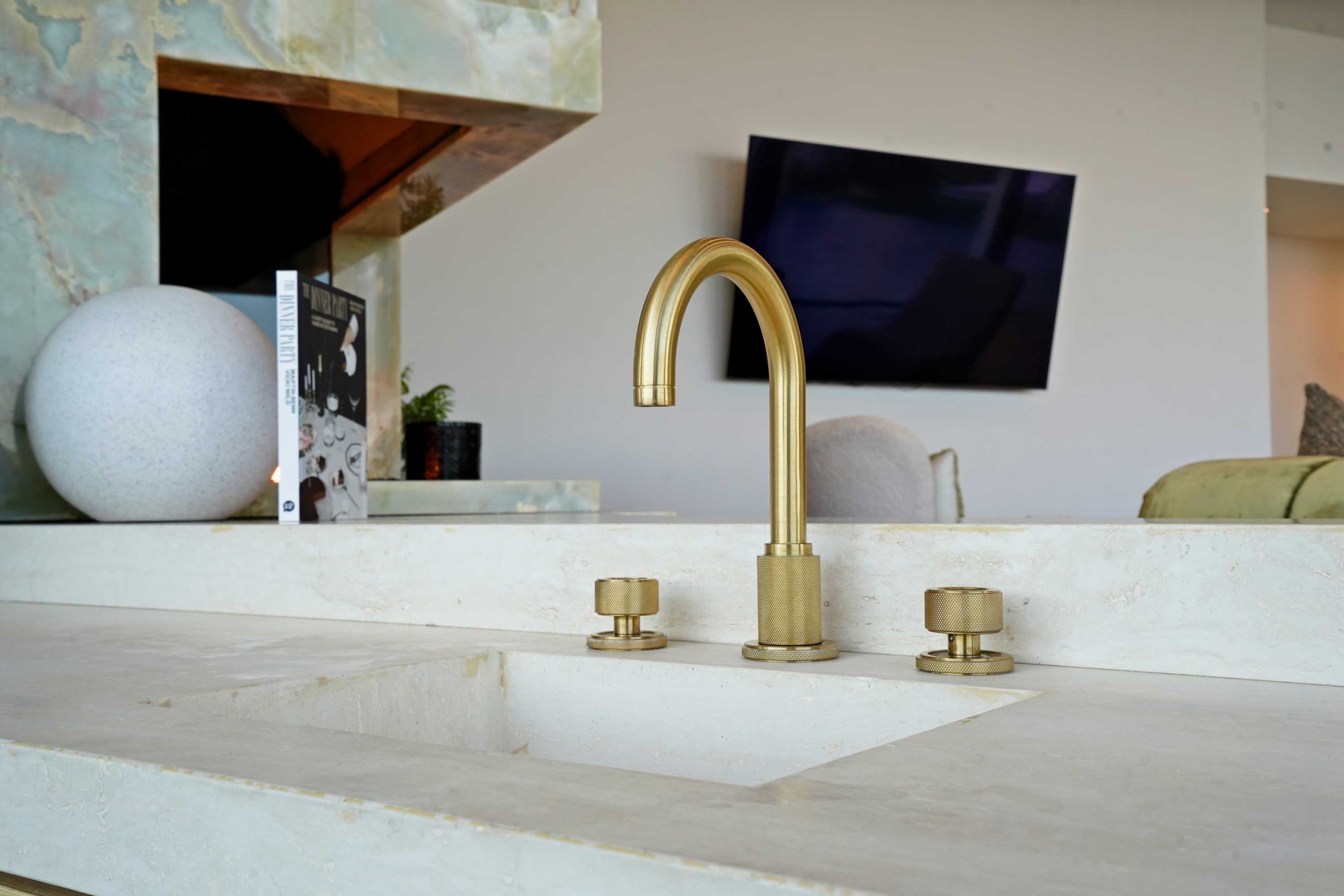 Sleek brass faucet atop a polished stone countertop, a statement of modern elegance.