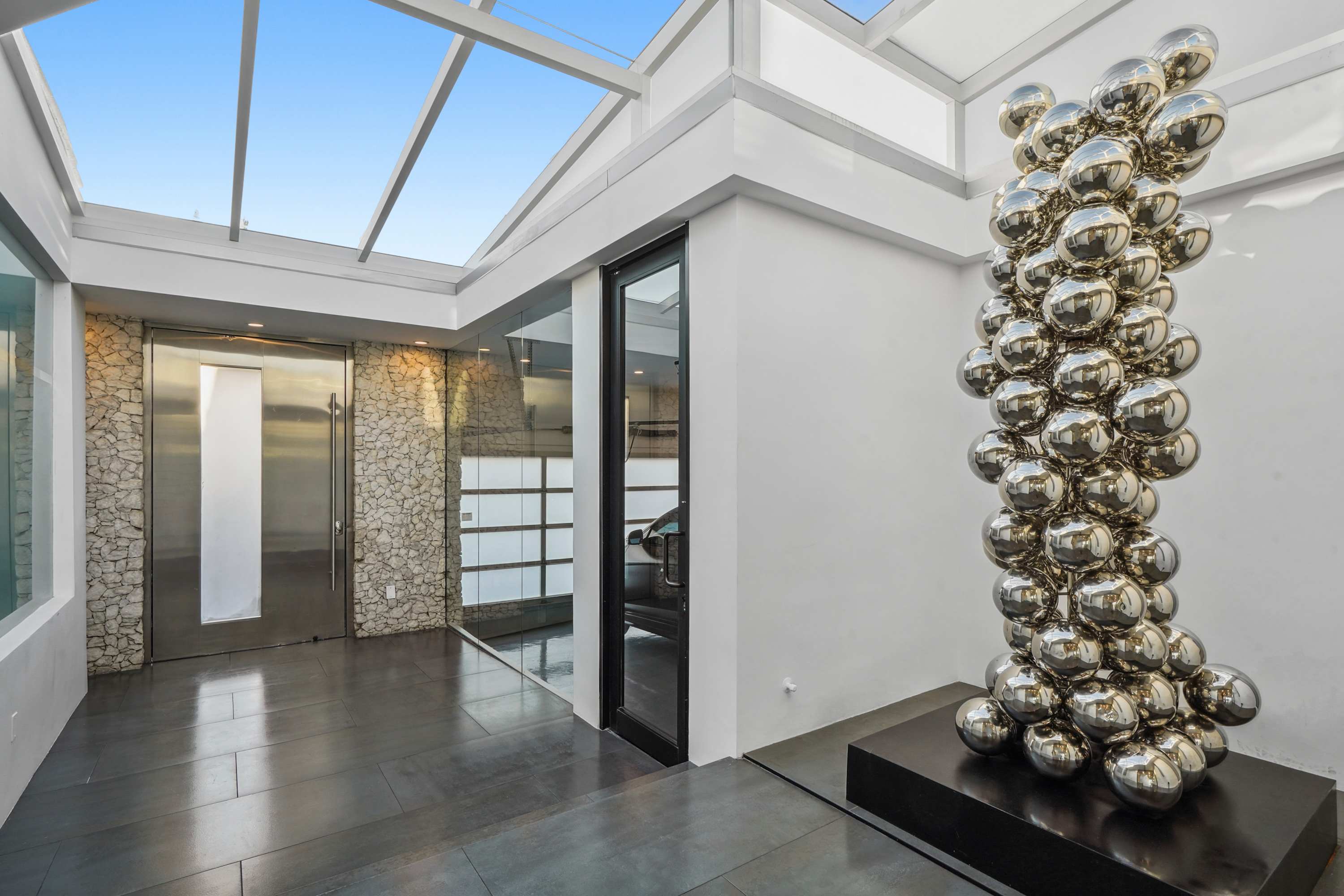 Transition through an airy atrium framed by glass, leading to the main living spaces.