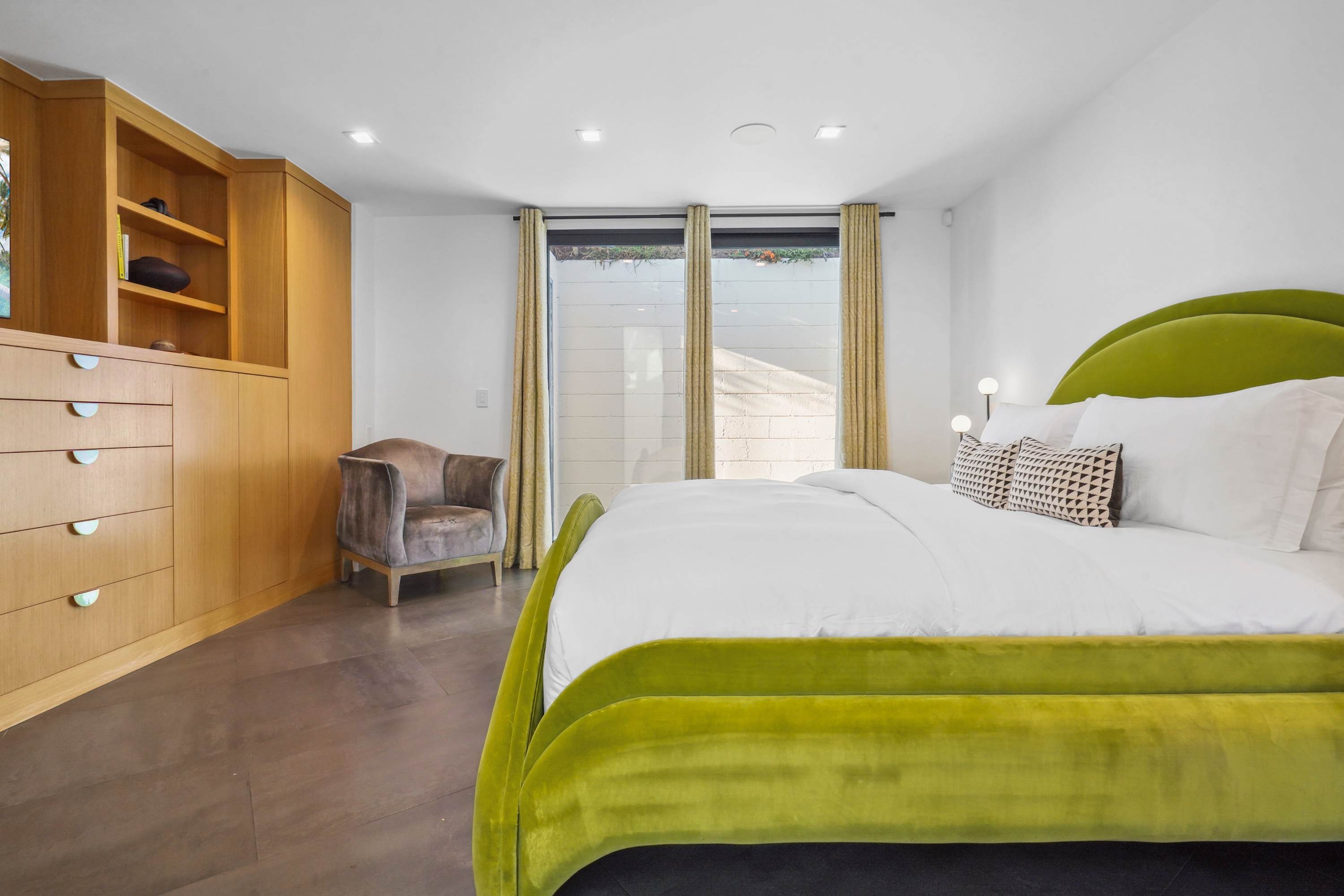 A spacious primary bedroom with a cozy sitting area, built-in storage, and expansive windows.