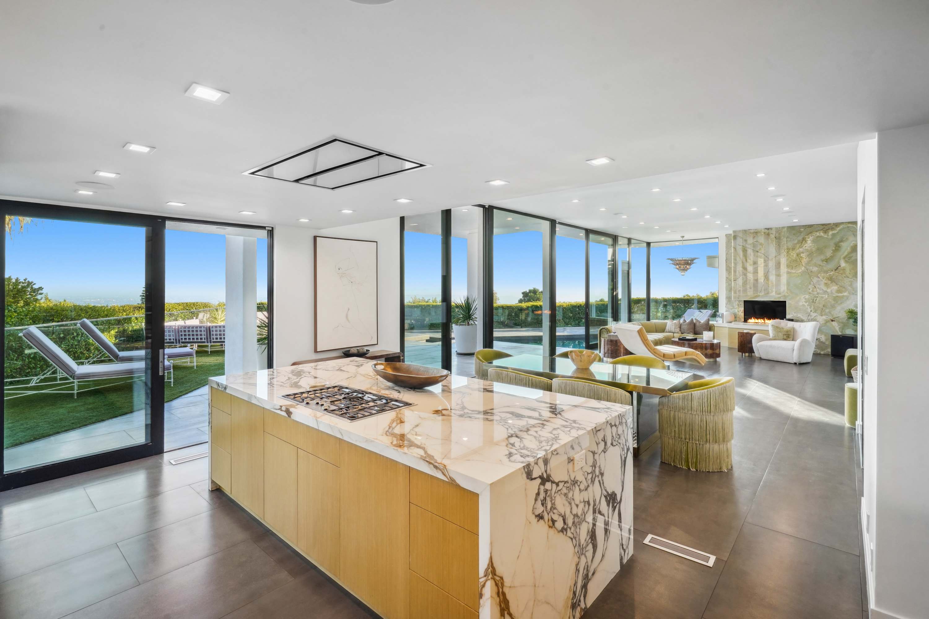 Marble island, custom cabinetry, and seamless indoor-outdoor flow with expansive glass doors.