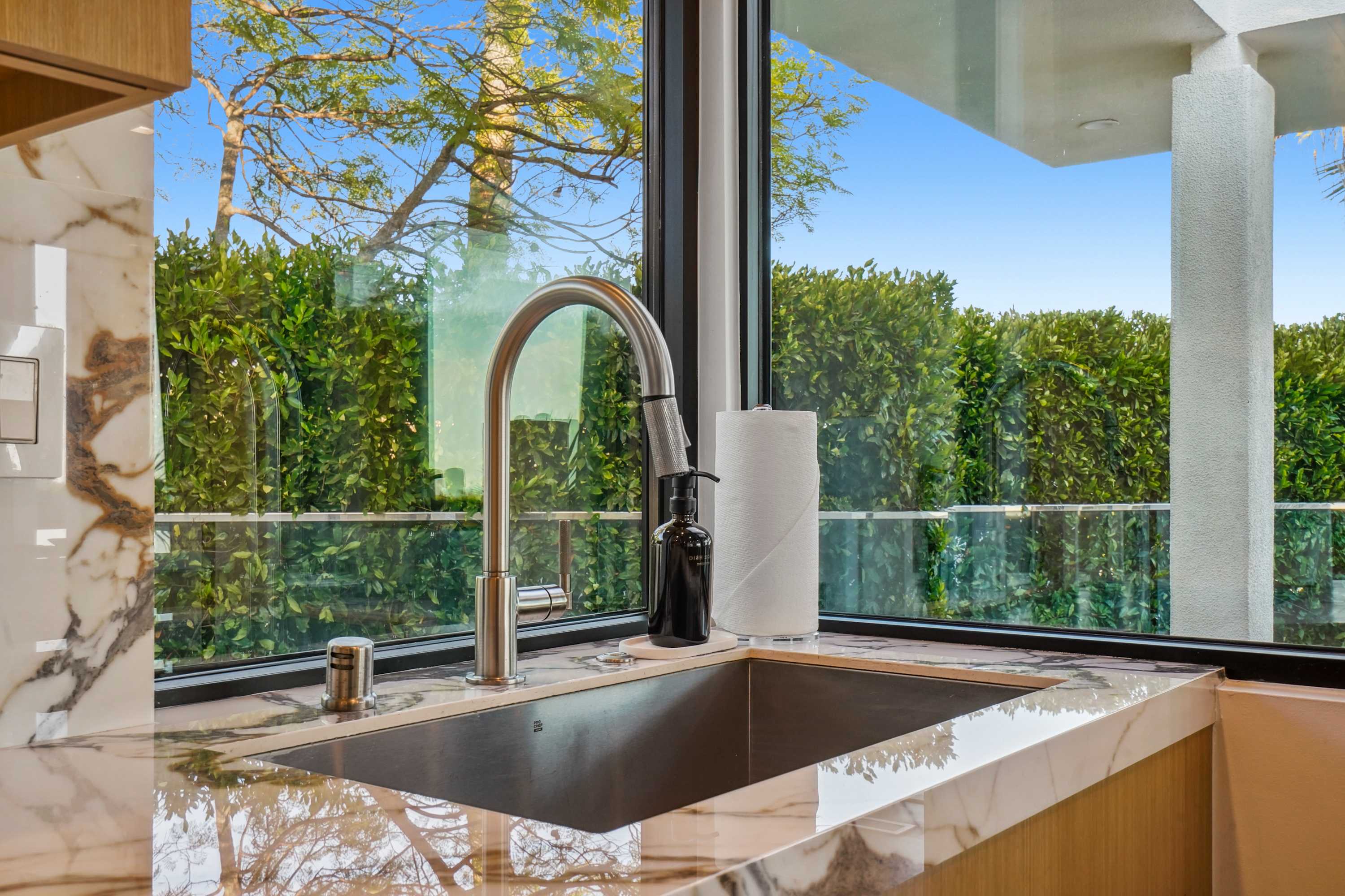 Polished marble countertops paired with serene garden views through expansive windows.