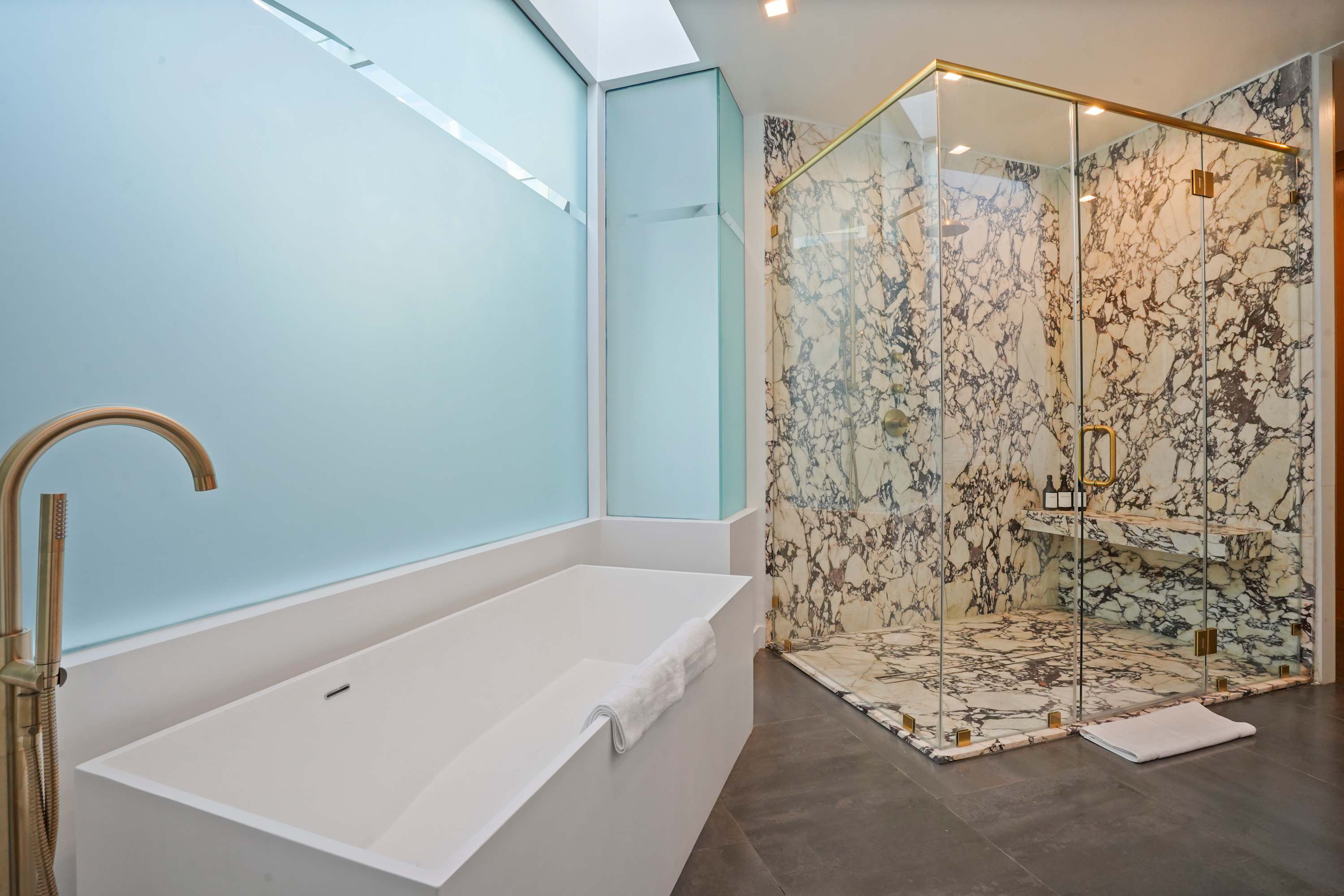Master bathroom featuring exquisite marble countertops, sleek gold fixtures, and a spacious glass-enclosed shower.