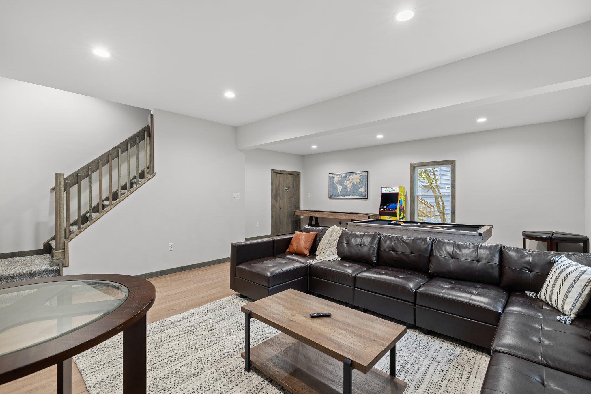 Lower-Level Lounge with Stairs View
Spacious and open with direct access to the game zone. A comfy sectional makes this the perfect spot to kick back and relax.
