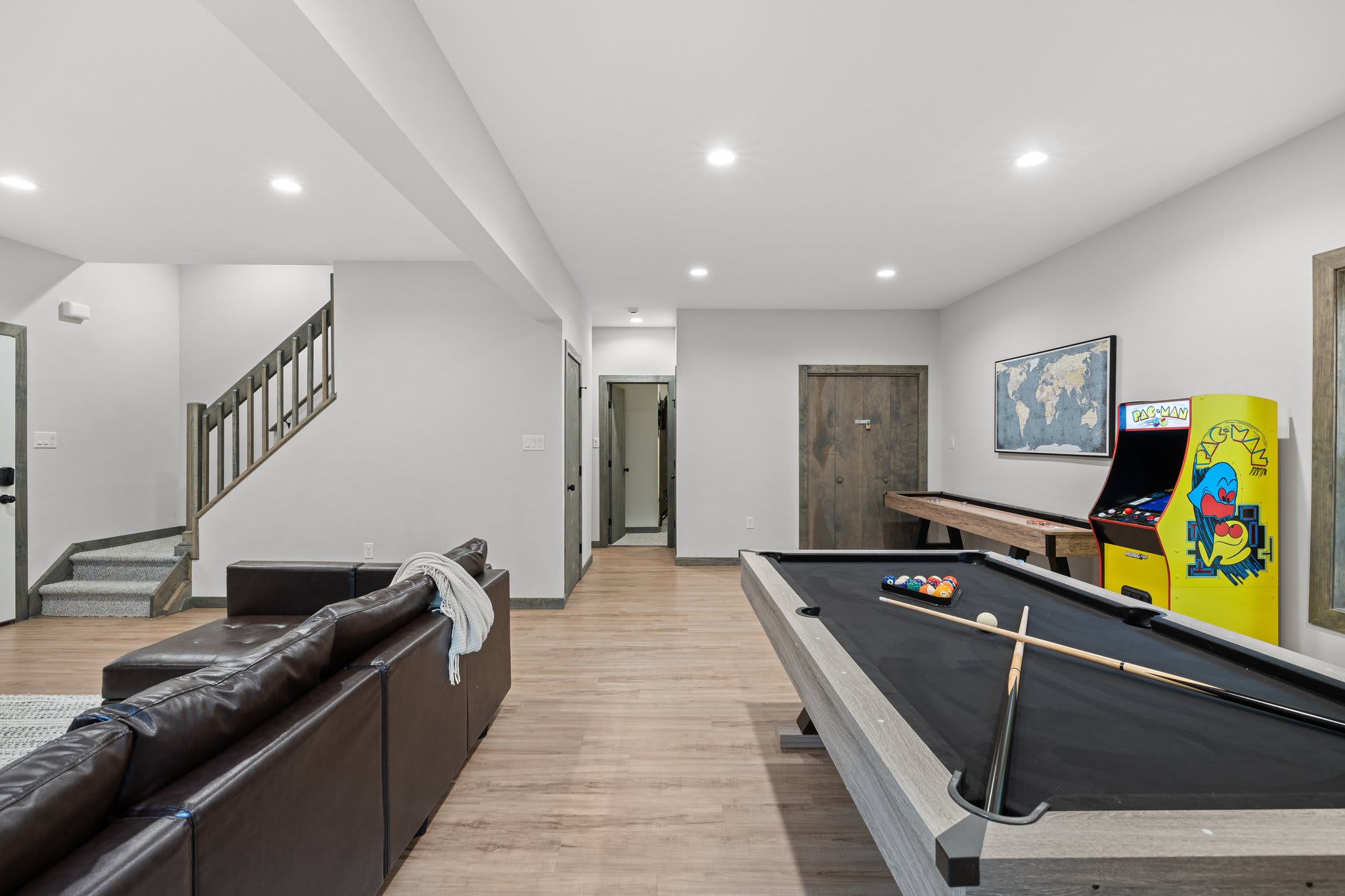 This view captures it all. Lounge seating, stairs to the upper level, and a full arcade and game lineup all in one open space.