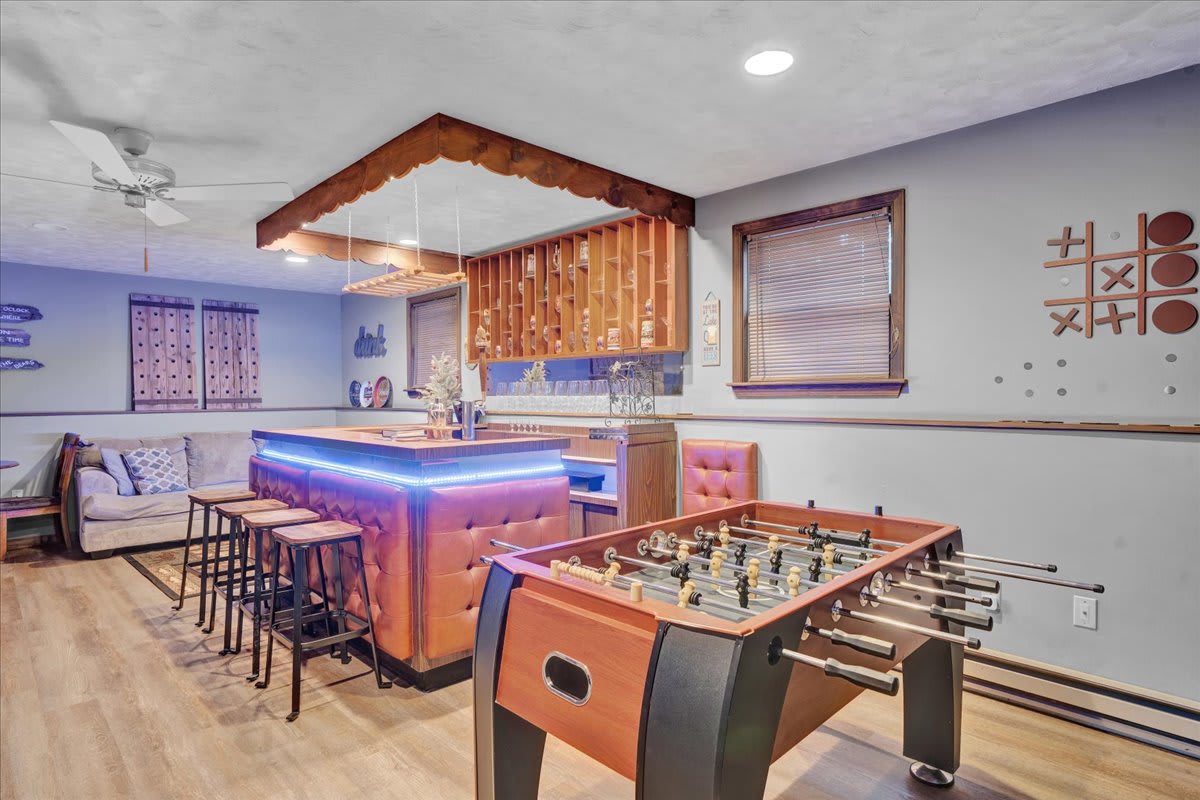 Game Night Paradise – A lively entertainment space featuring a foosball table, stylish bar seating, and warm wooden accents, perfect for fun-filled evenings.