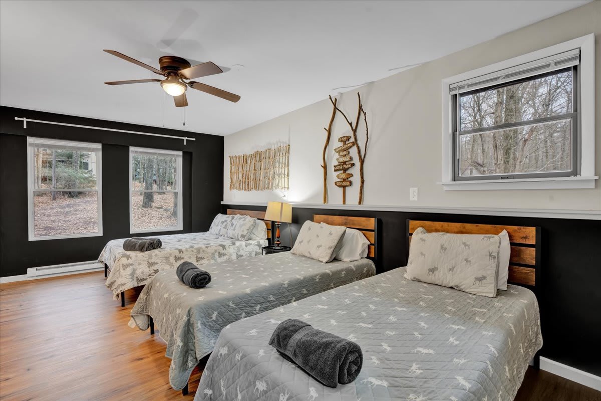 Spacious & Modern Room – A beautifully designed bedroom featuring one double bed and two single beds, soft textures, and natural light for a fresh and airy ambiance.