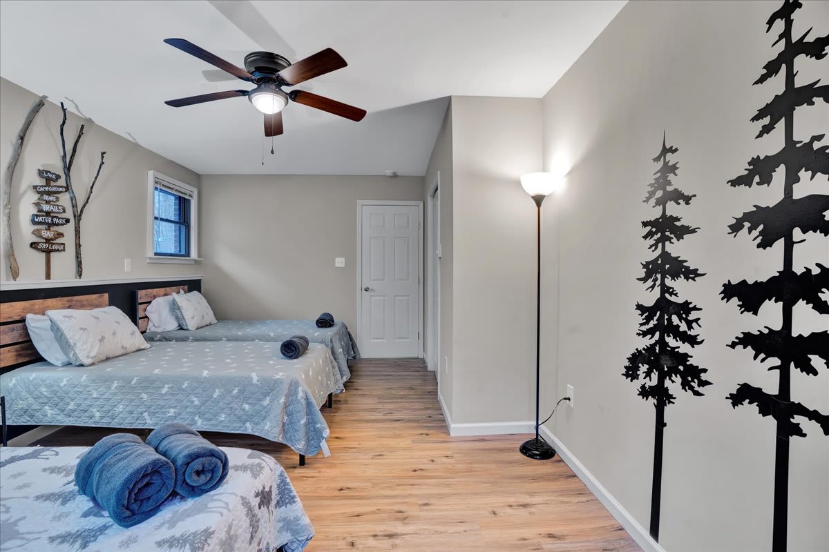 Charming & Airy Sleeping Space – Soft lighting, playful tree decals, and comfortable beds make this the perfect room for a restful stay.