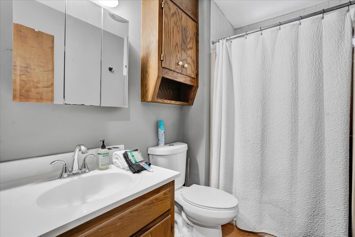 Simple & Functional Bath Space – A classic bathroom design with wooden accents, bright lighting, and all the essentials for a refreshing experience.