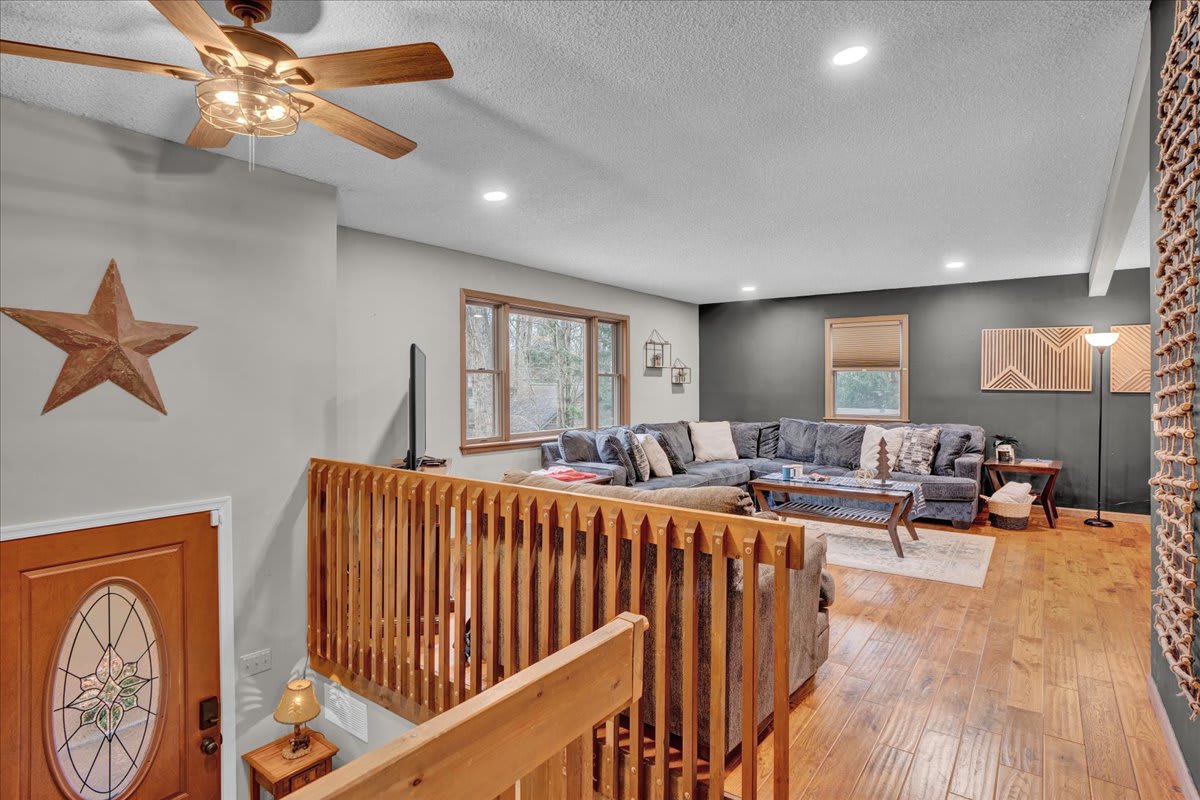 Inviting Loft-Style Living Room – A spacious and airy living area with vaulted ceilings, warm wood accents, and a stylish open staircase for a rustic-modern charm.