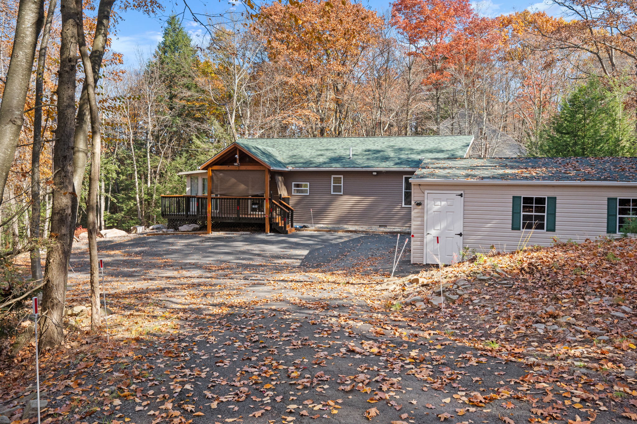 A spacious driveway welcomes you to this cozy mountain escape, surrounded by vibrant seasonal foliage.