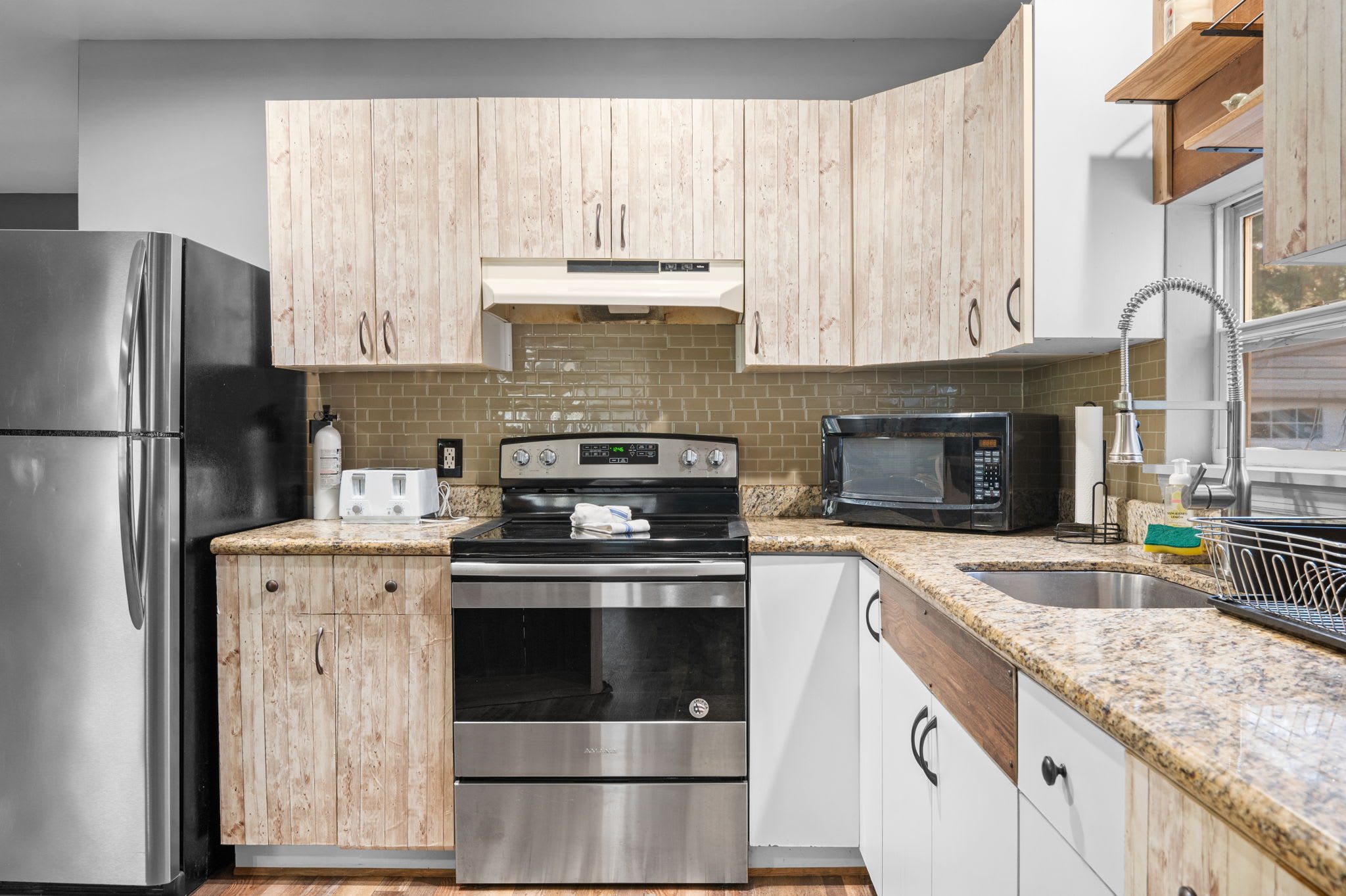 Granite countertops and a sleek tile backsplash create a polished cooking space that’s both functional and inviting.