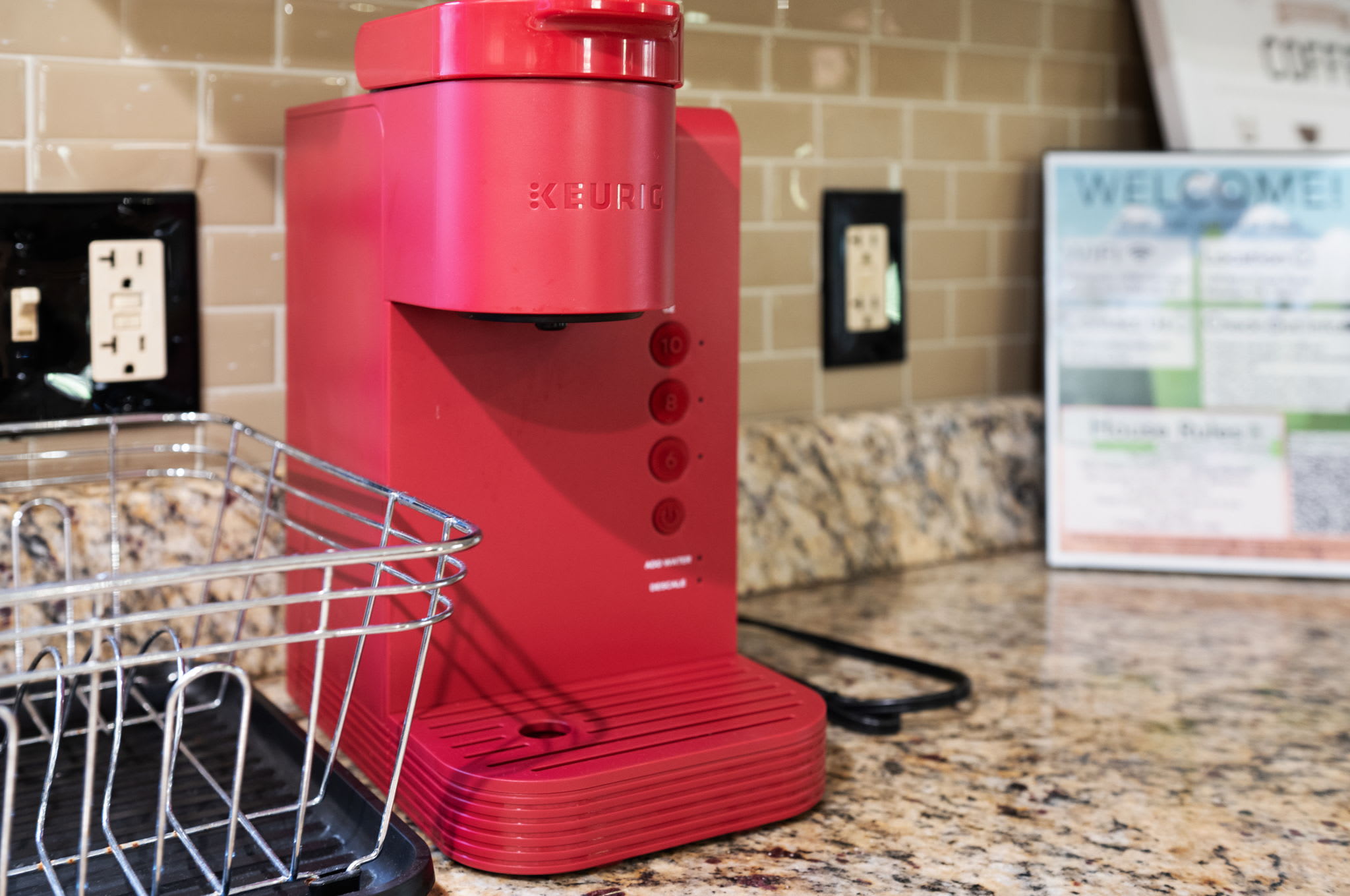 A bright red coffee maker stands ready on the granite countertop, perfect for morning brews or afternoon pick-me-ups.