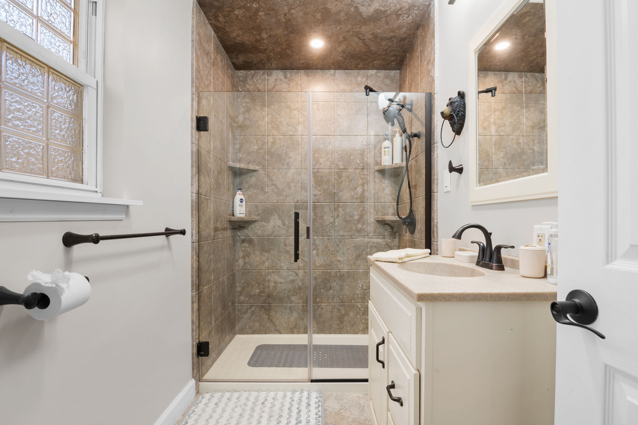 The bright vanity and sleek black fixtures provide a modern contrast against the earthy tones.