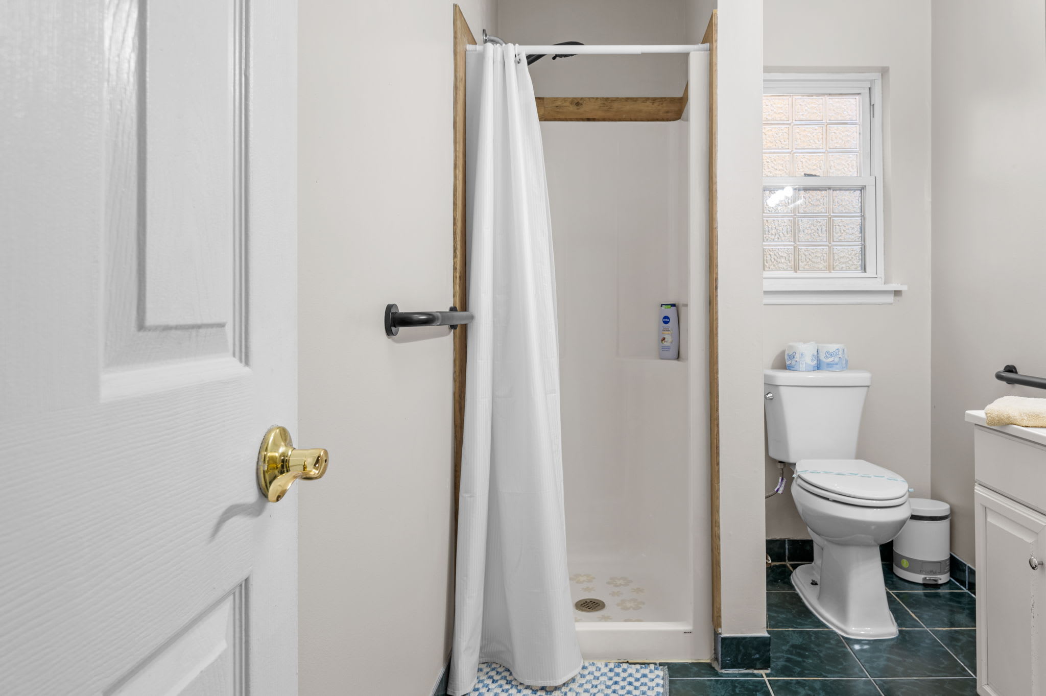 Green-tiled floors complement the neutral walls, adding a refreshing pop of color.