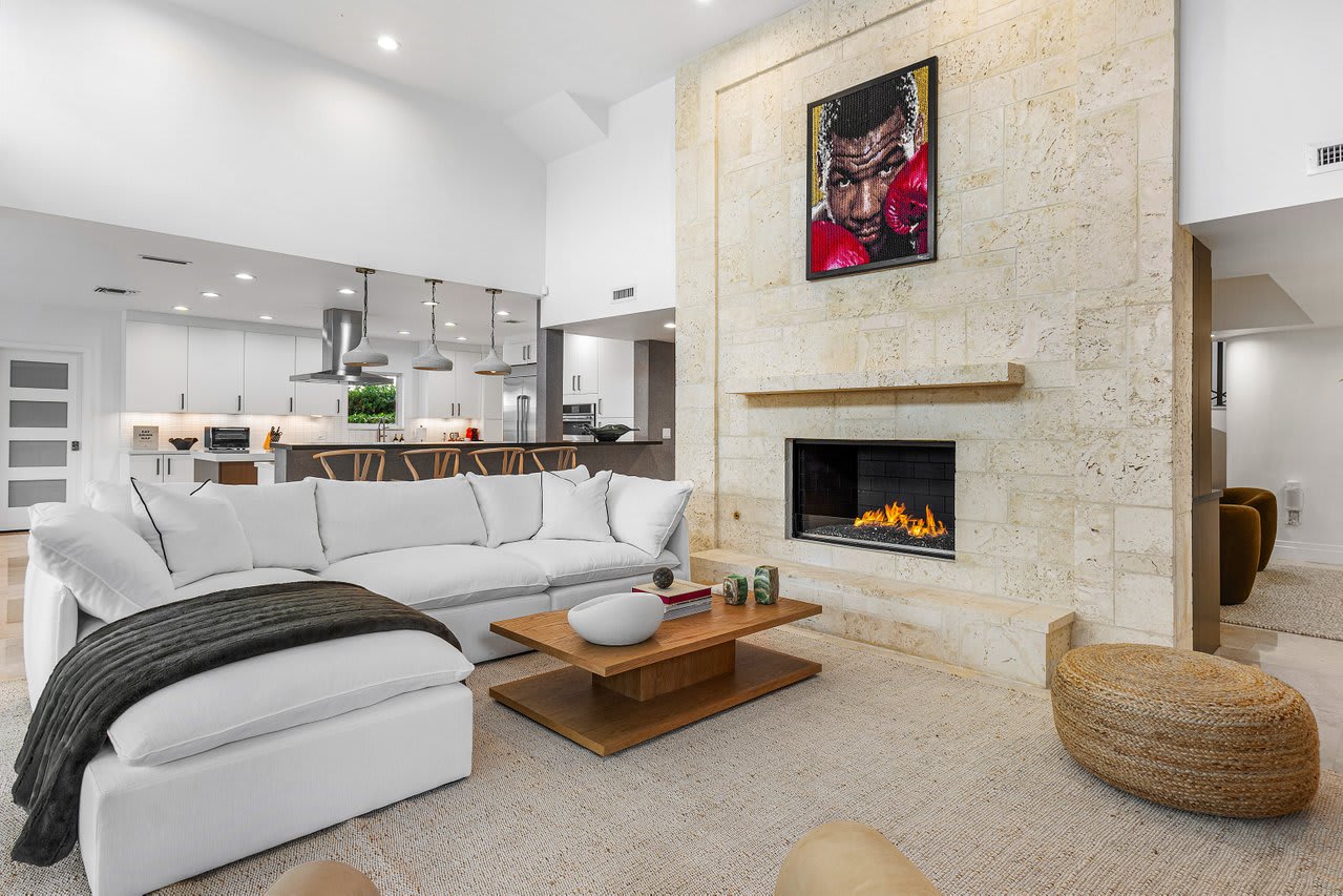 Stone-lined fireplace anchors a modern living space with soft textures and polished finishes.
