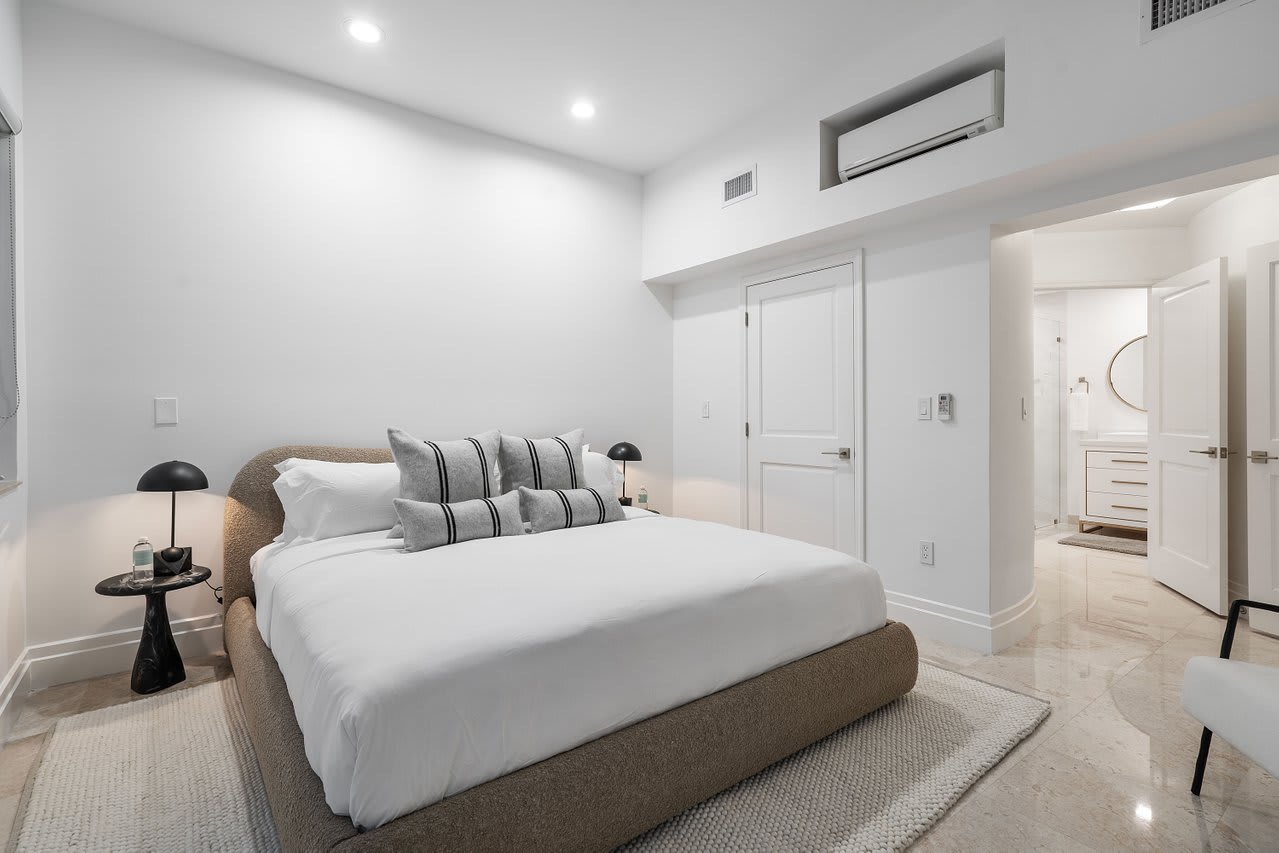 A serene escape featuring a plush king bed, soft linen, and marble flooring, complete with ample closet space and ambient lighting.