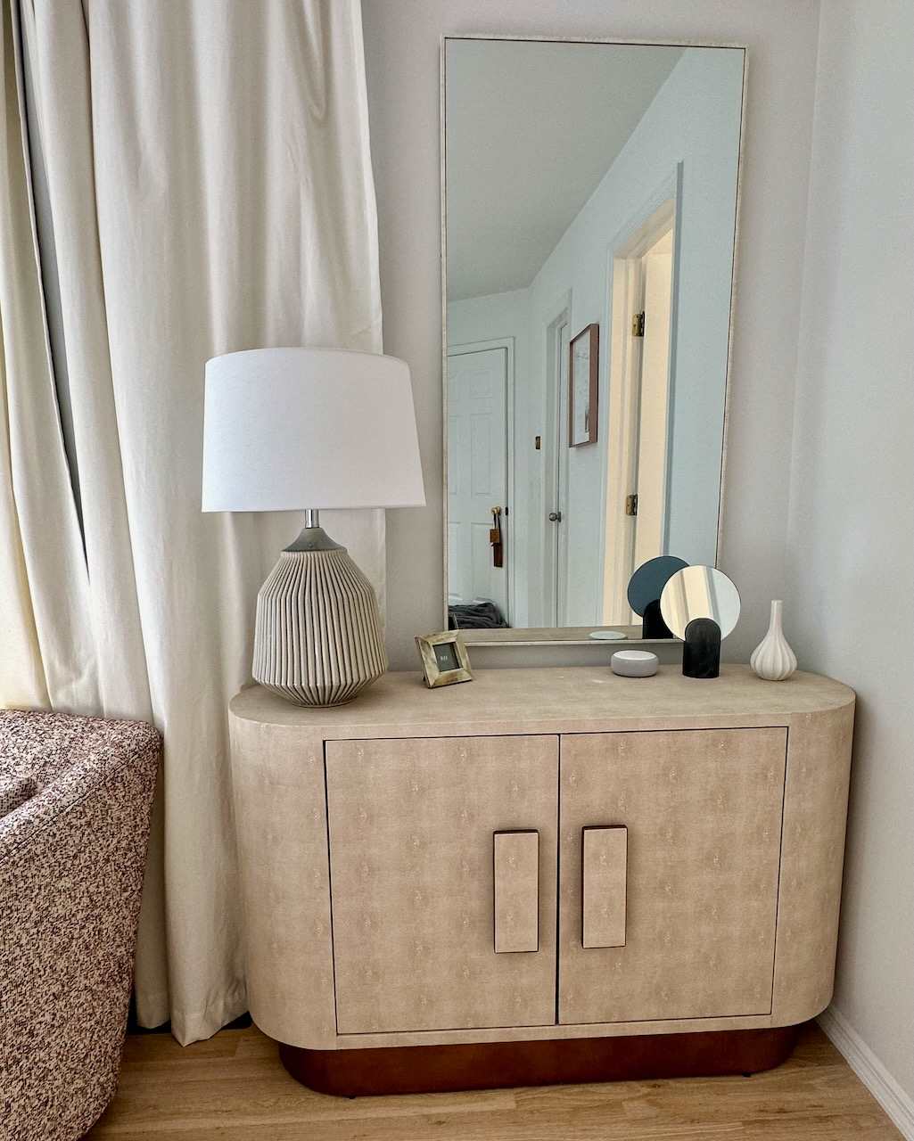 Bedroom console table with a lamp, mirror, and decorative accents.