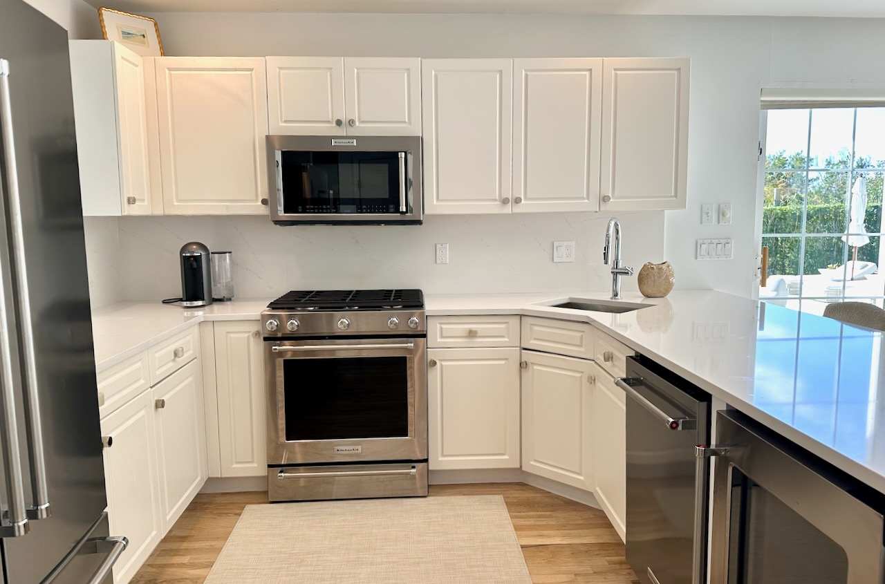 Kitchen with cream cabinetry, stainless range and microwave, and a garden-view window.