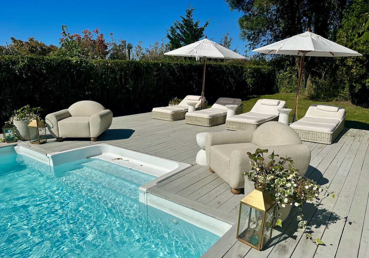 Pool with a sun shelf, lounge chairs, and umbrellas on the deck.