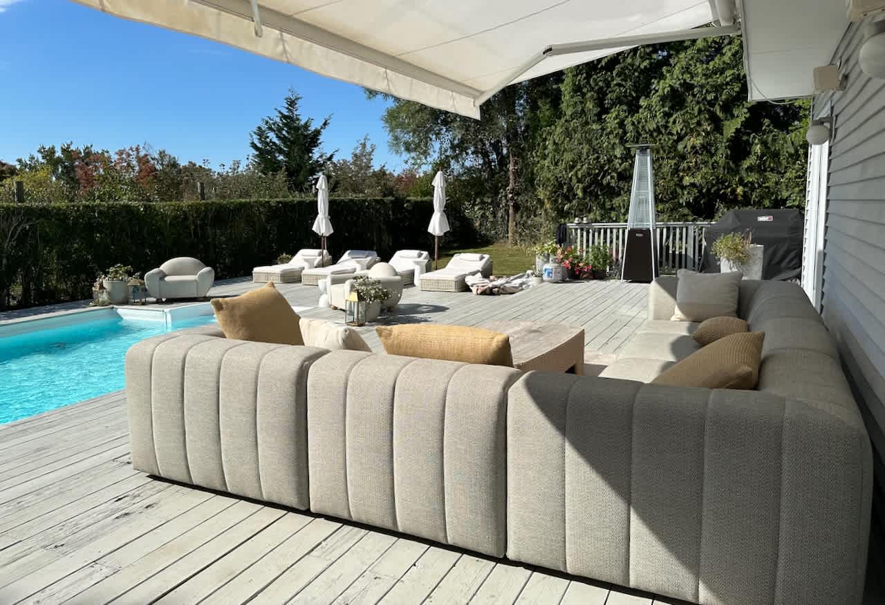 Covered patio with a large sectional sofa and pool view beneath a retractable awning.