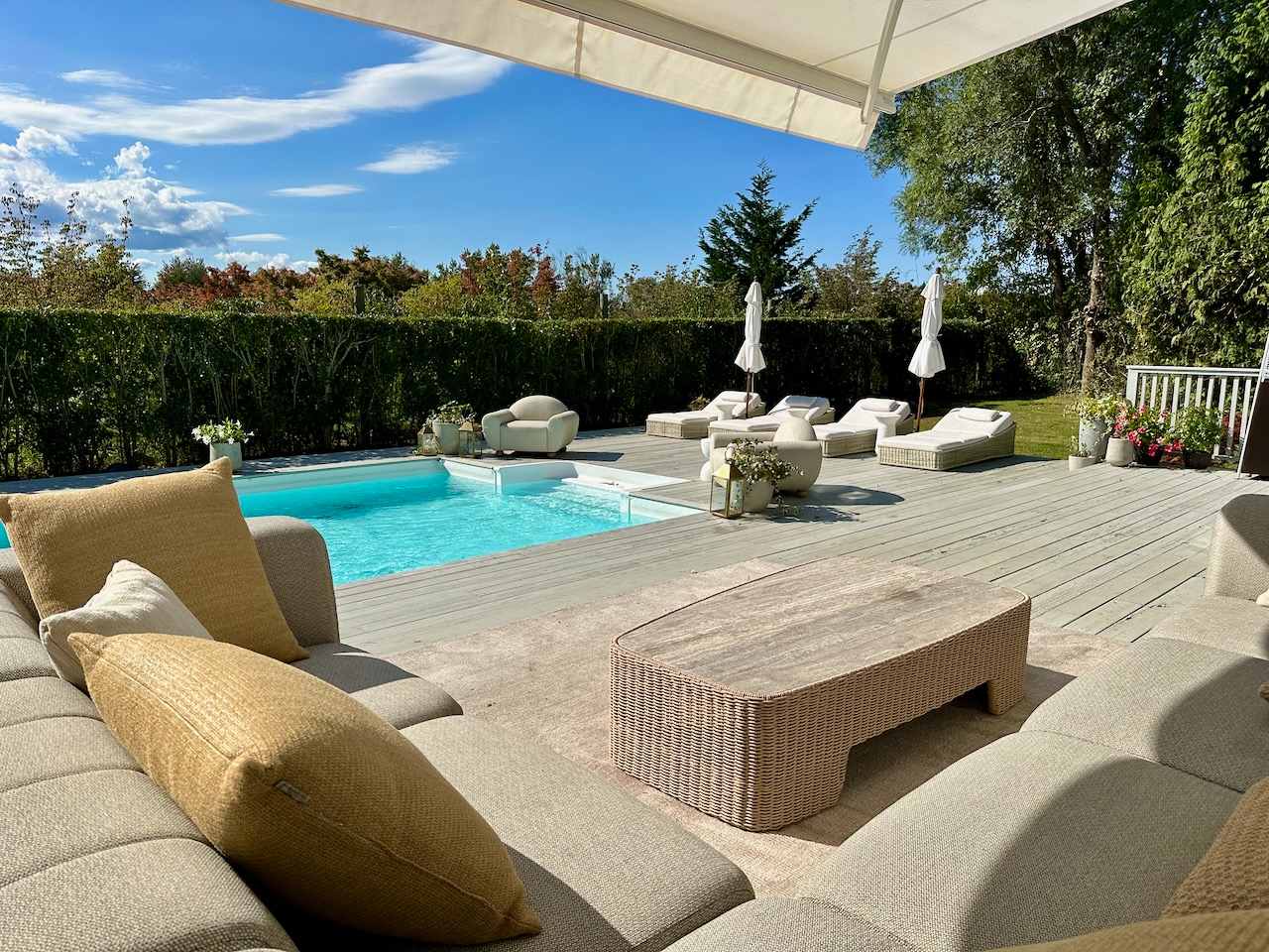 Covered patio lounge seating with a wicker coffee table and pool view.