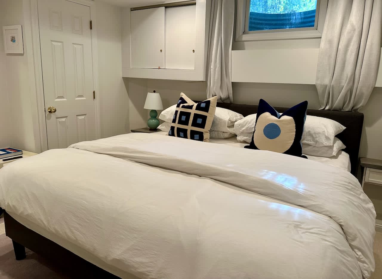 Bedroom with a queen bed, graphic throw pillows, and a built-in closet nook.
