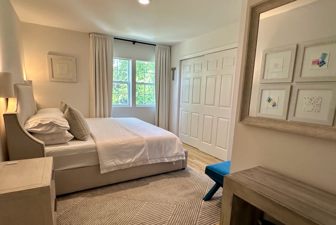 Bedroom with a queen bed, gallery-framed artwork, and a built-in closet wall.