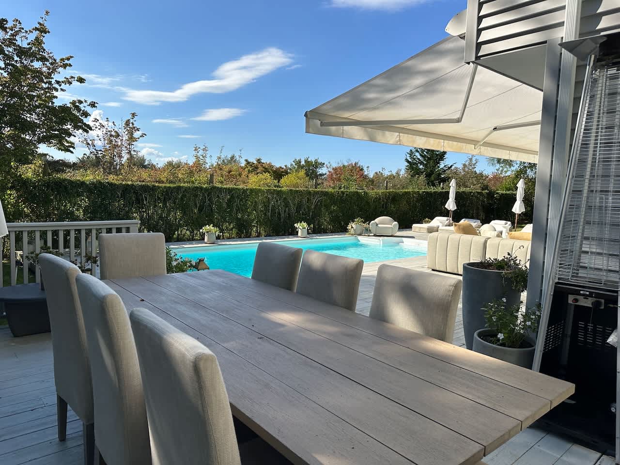 Outdoor dining table under the covered patio awning, with the pool visible beyond.